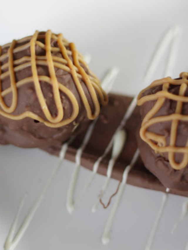 Chocolate truffles with peanut butter drizzle on a white plate with chocolate sticks.