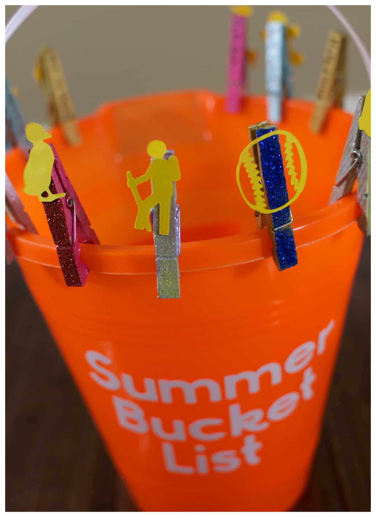 Colorful clothespins attached to an orange bucket labeled "Make Your Own Summer Bucket List".