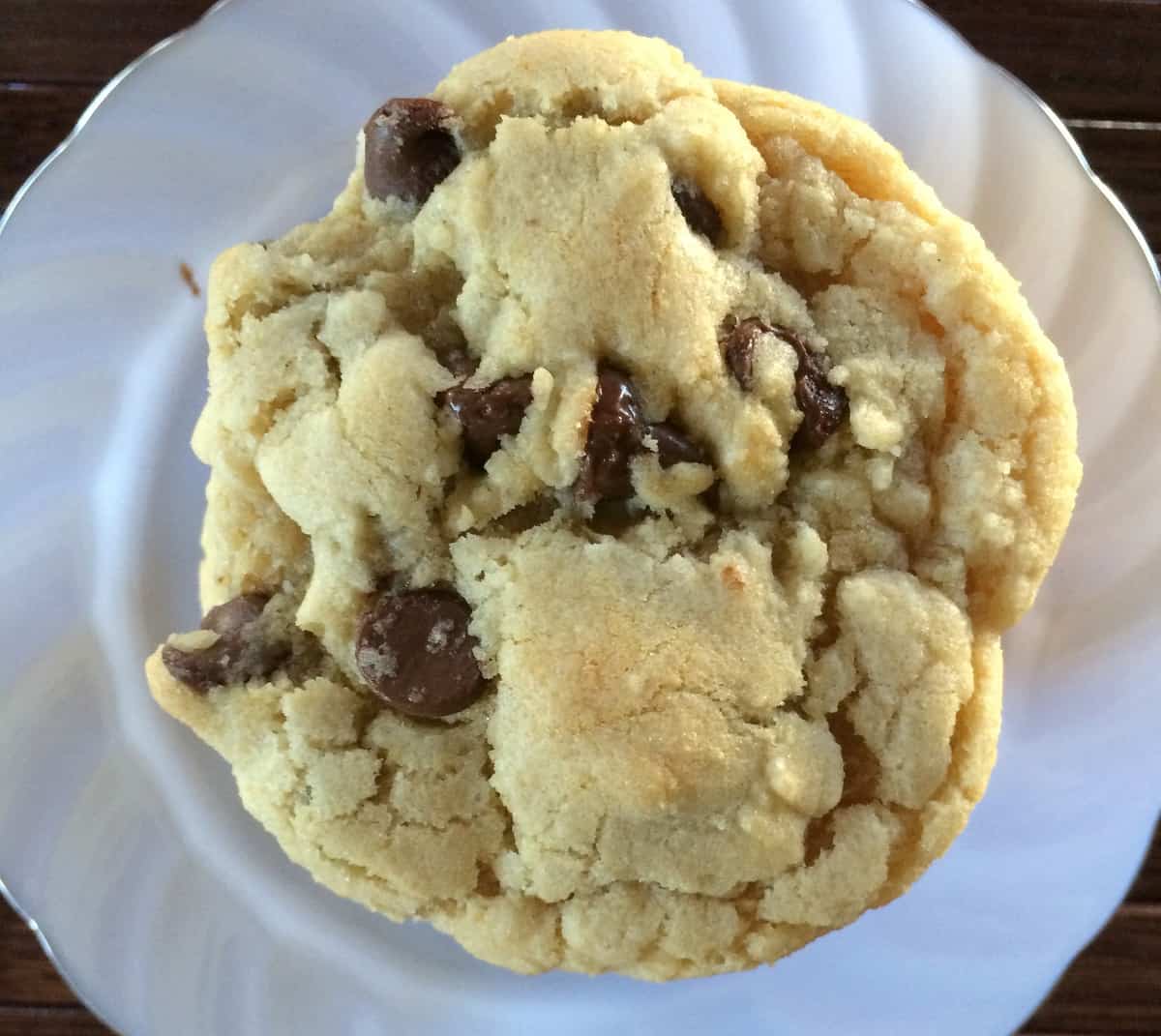 A freshly baked M&M chocolate chip cookie on a white plate.