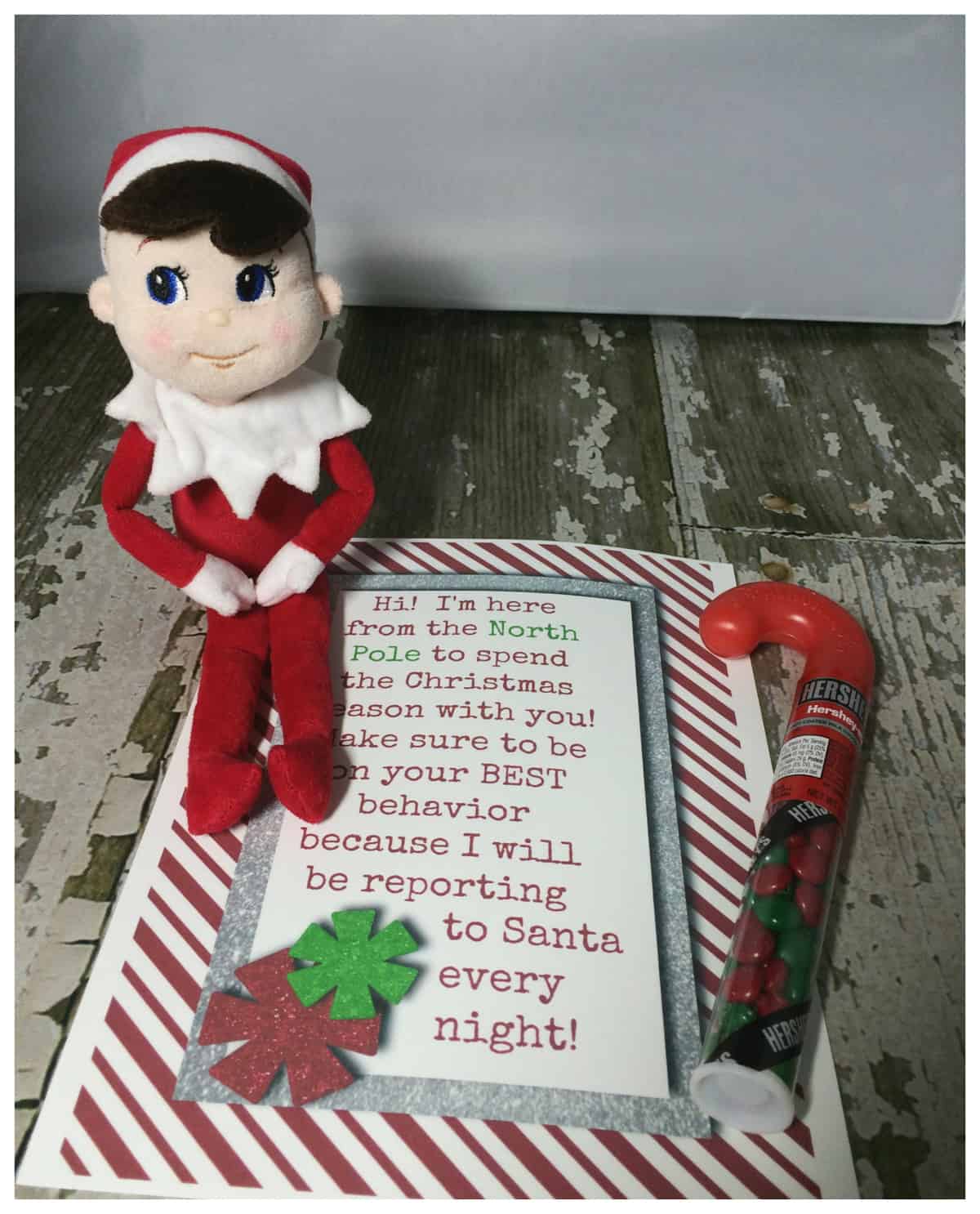 A plush elf doll accompanied by a welcome note, elf on the shelf printables free, and a candy cane, introducing the start of a Christmas Elf on the Shelf tradition.