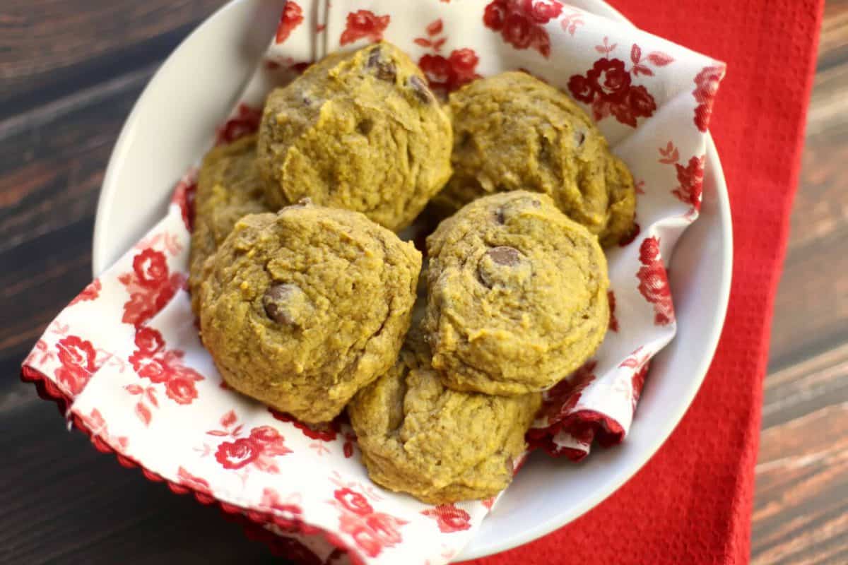 A bowl of homemade pumpkin cookies on a red floral napkin.
