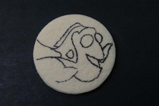 A Finding Dory sugar cookie with an outline of a fish character drawn on it.