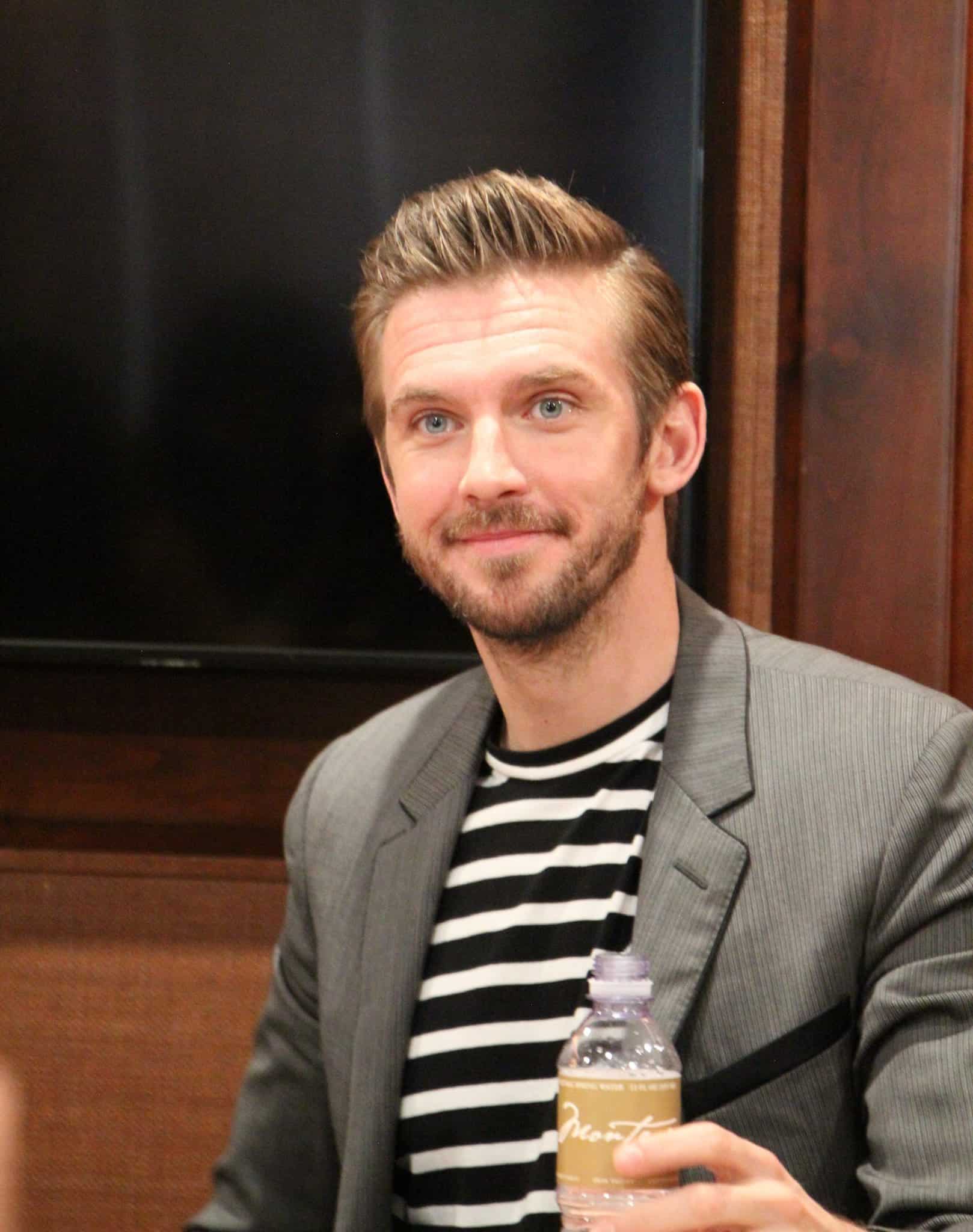 Dan Stevens holding a wine glass posing for the camera, with Beast and Belle