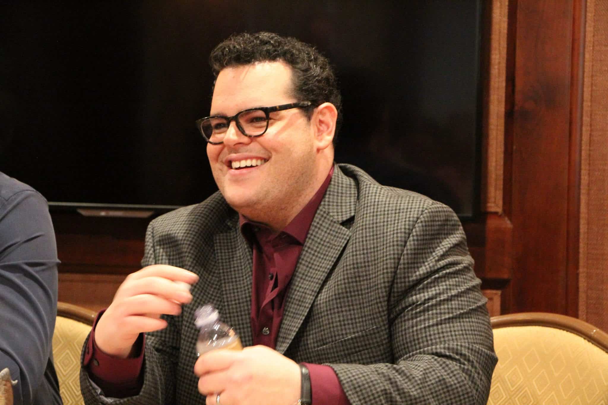 Josh Gad sitting at a table with wine glasses, with Luke Evans and Interview