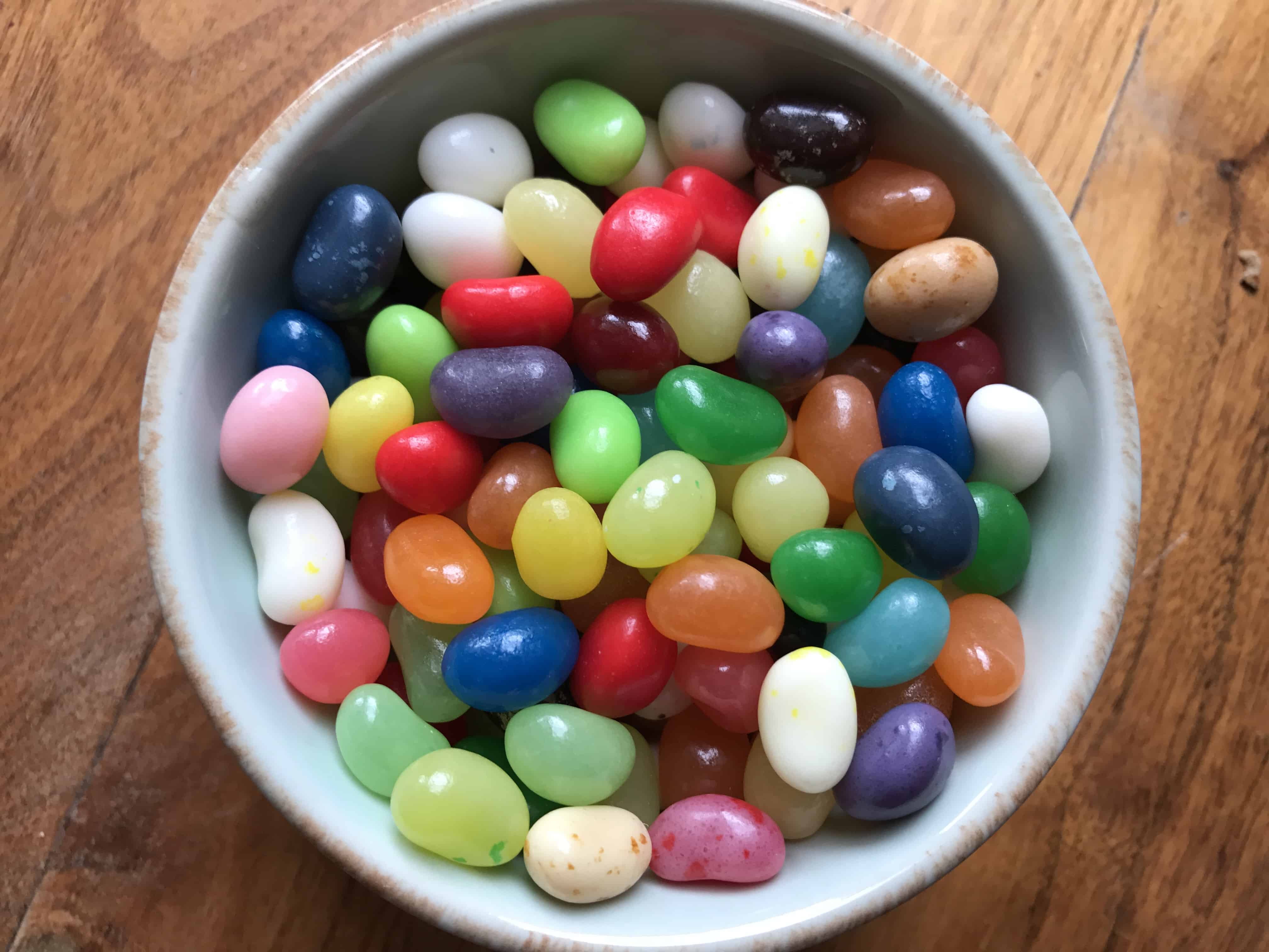 A bowl of food sitting on top of a wooden table, with Cupcake and Jelly bean