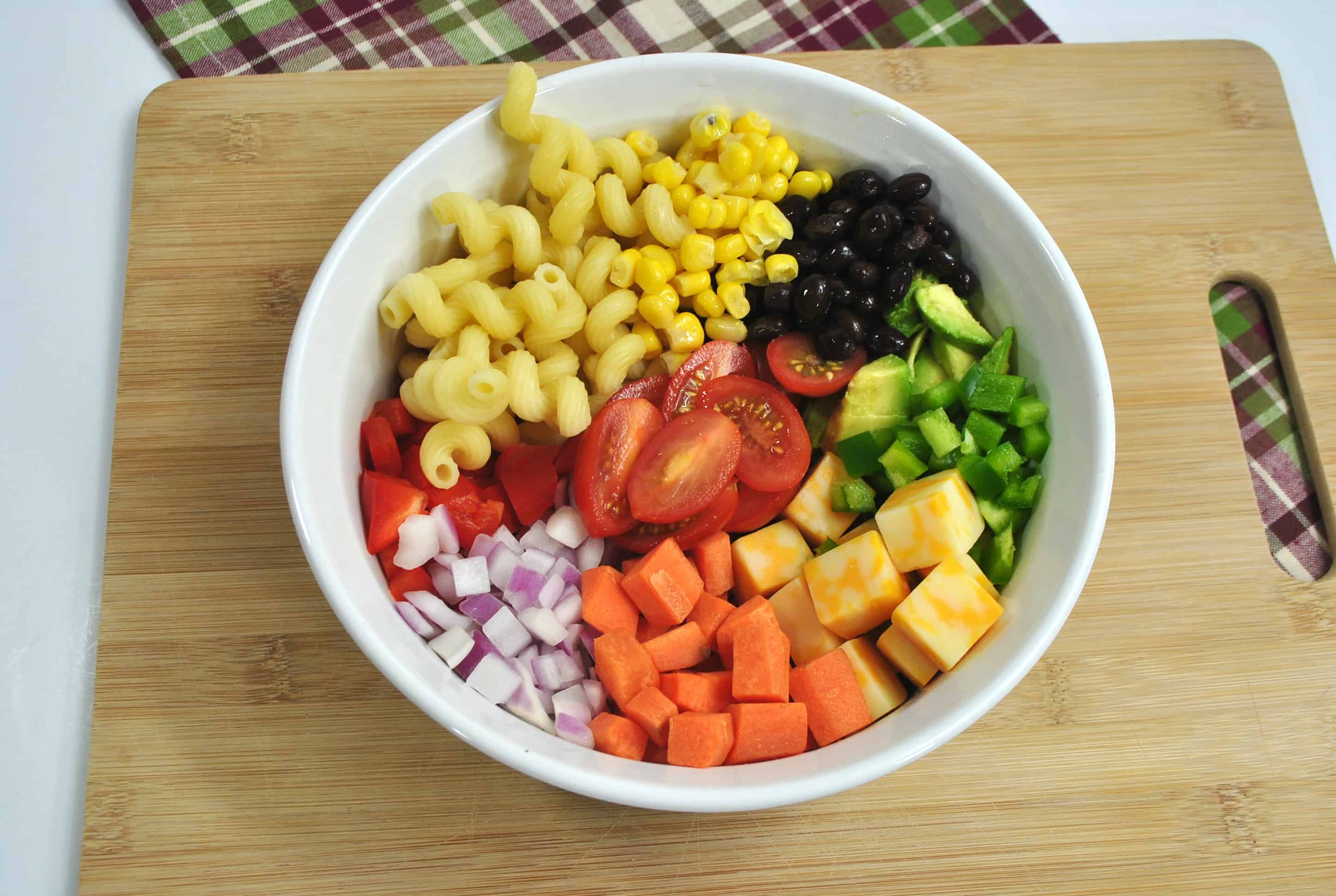 A bowl of fruit sitting on top of a wooden table, with Salad and Pasta