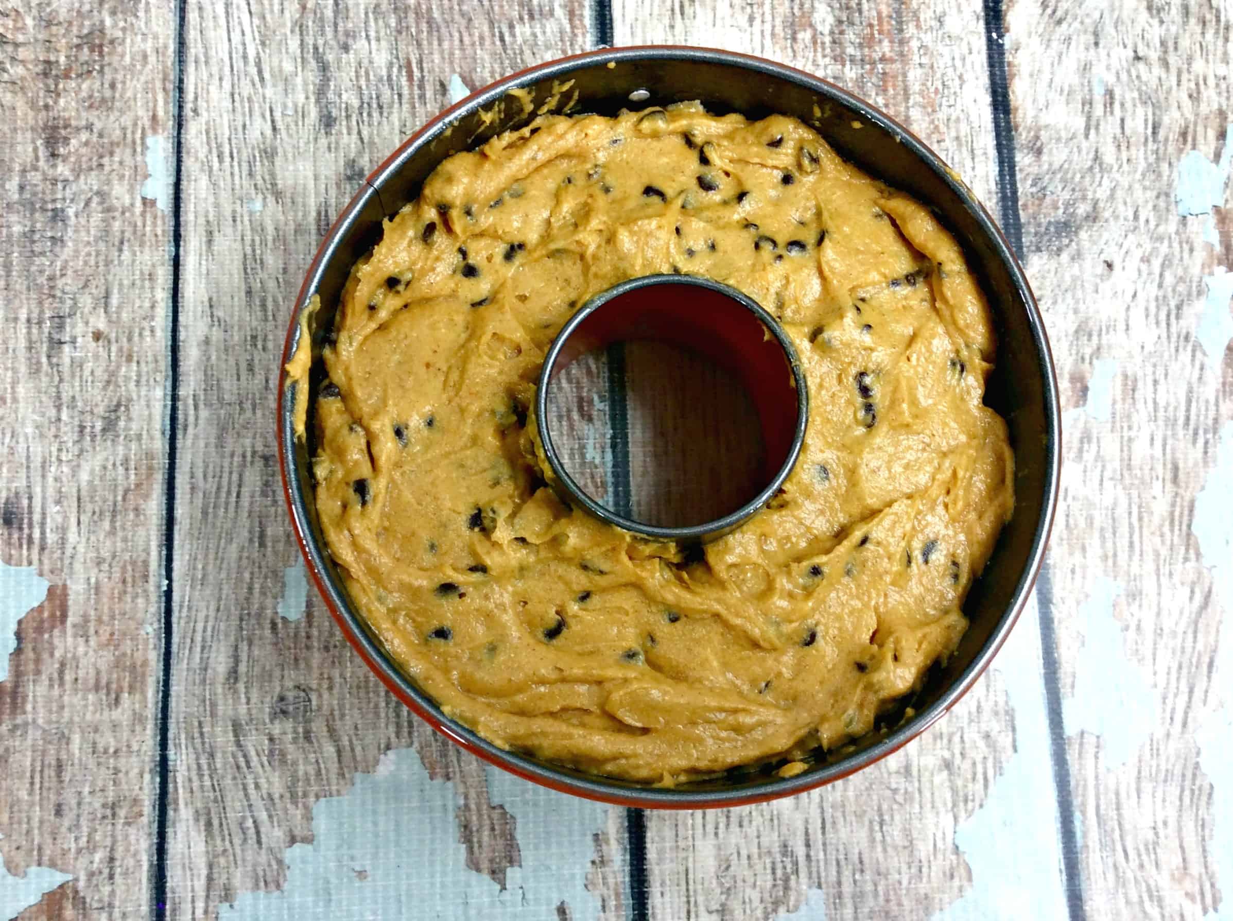 A bowl of food on a wooden table, with Pumpkin and Cake