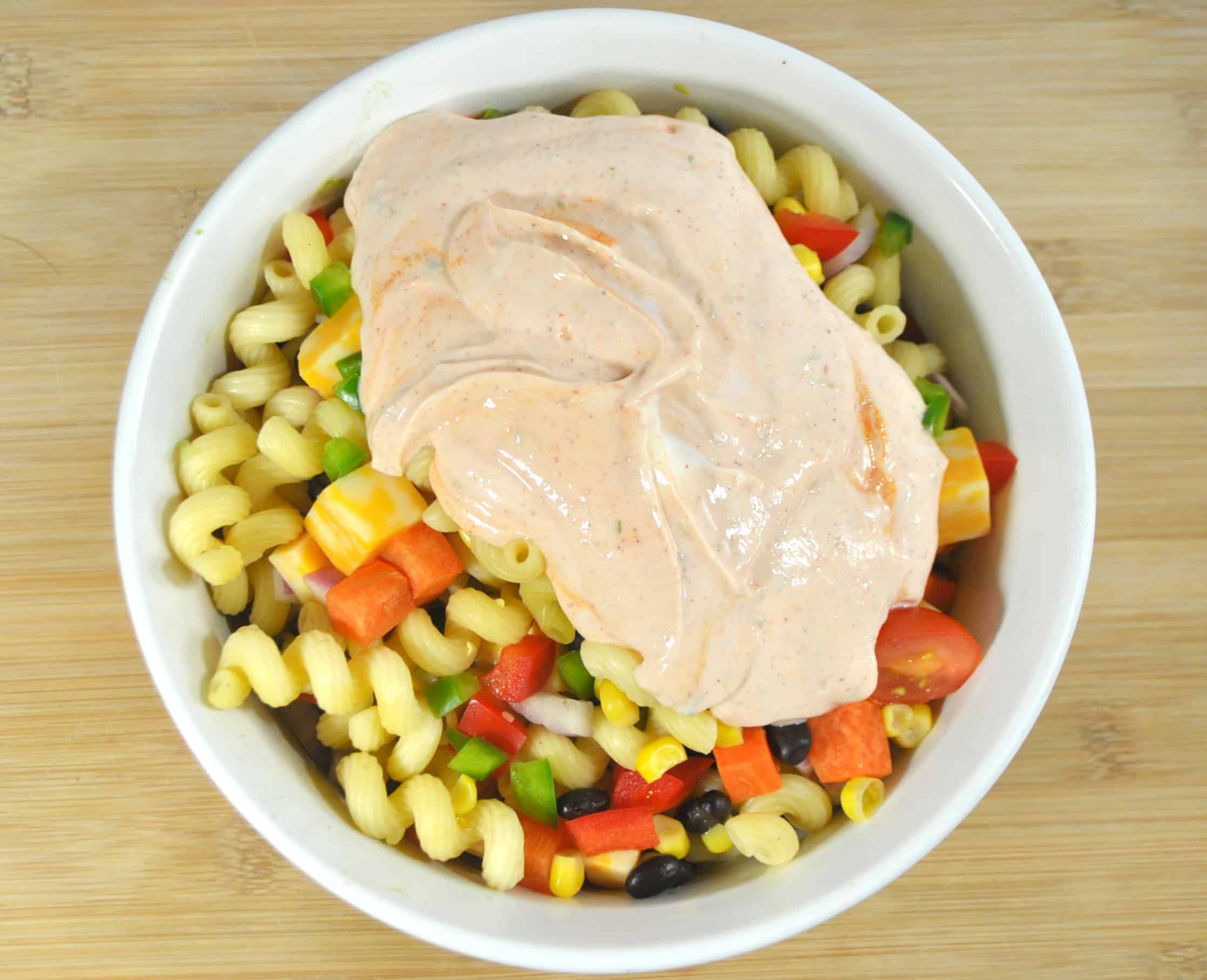 A bowl of food on a plate, with Salad and Pasta