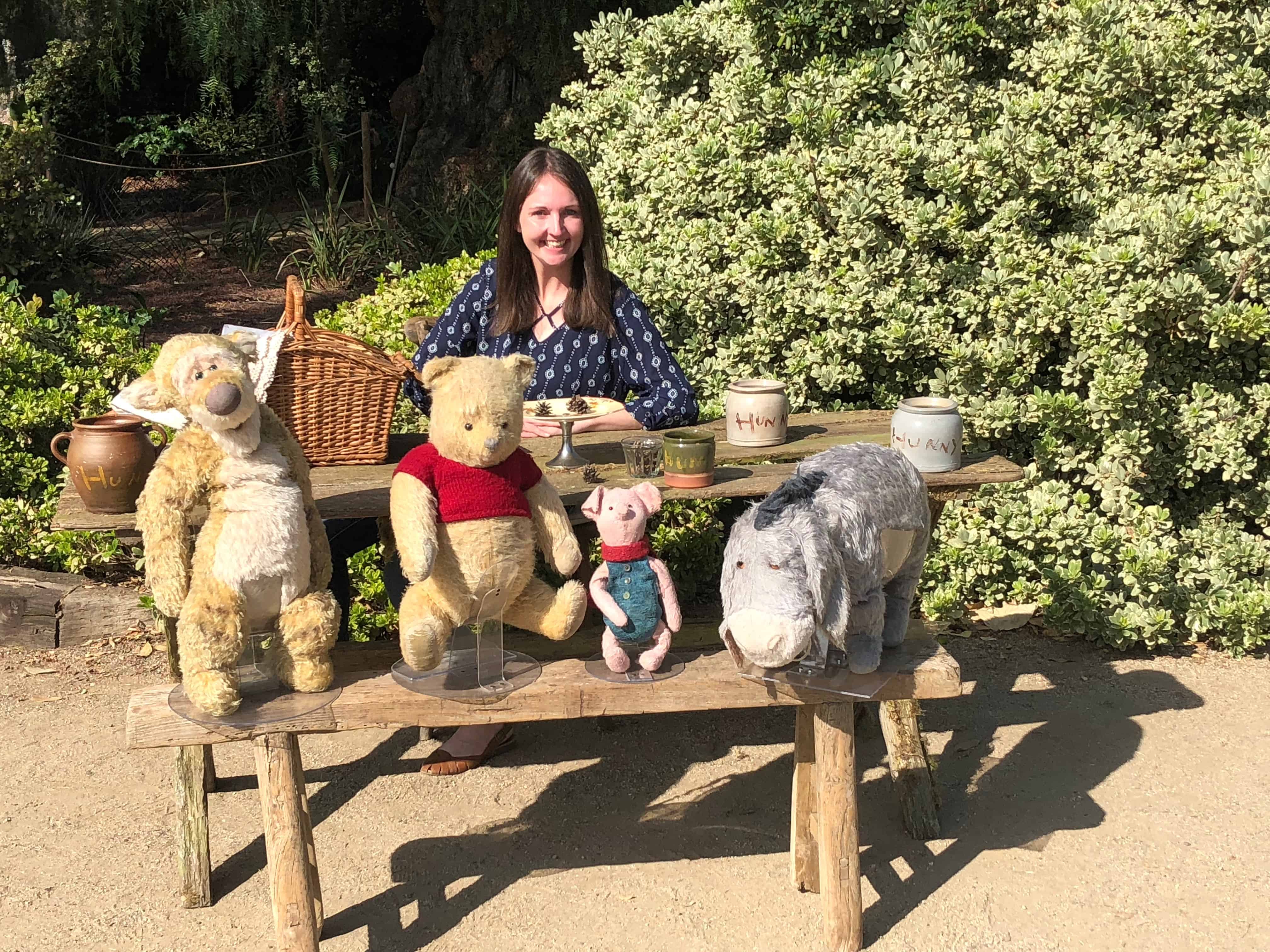 A person sitting on a bench next to a stuffed animal