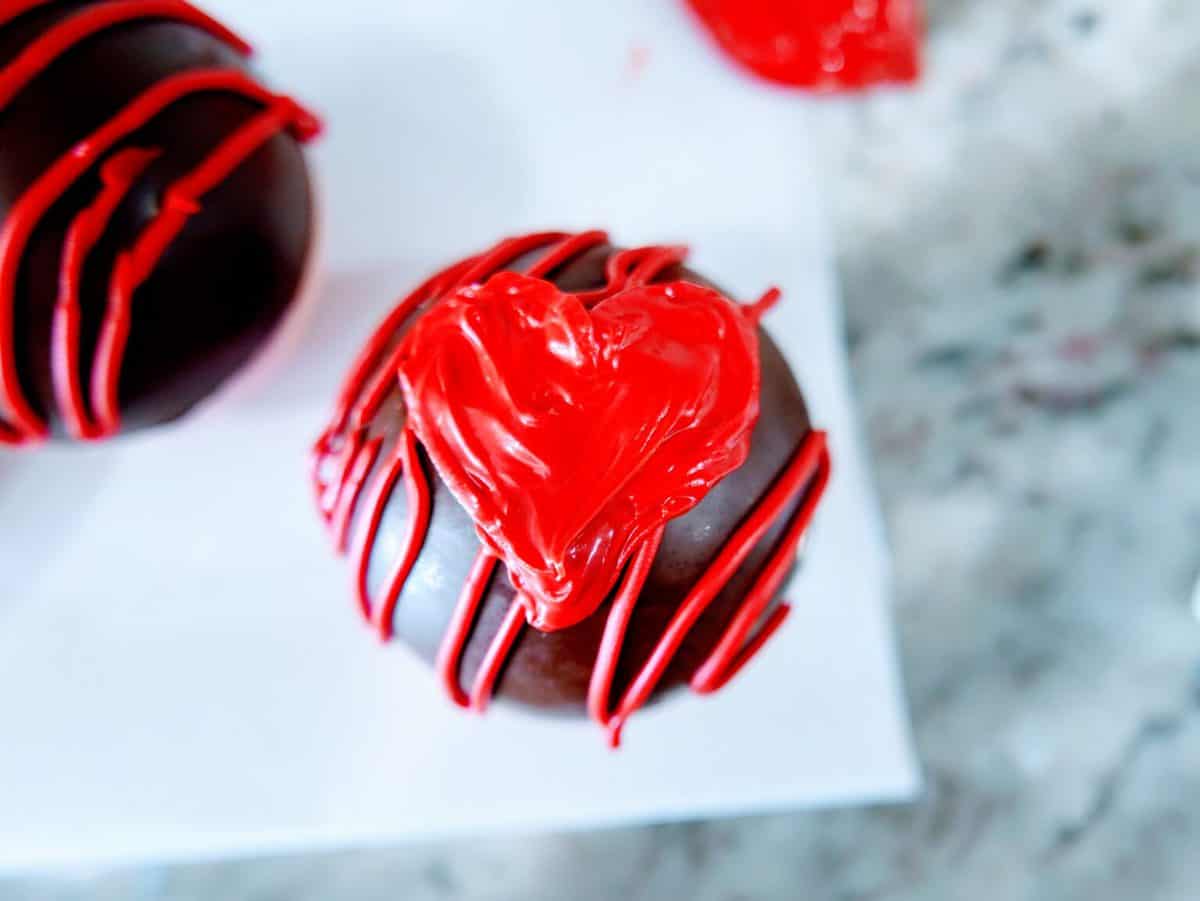 A chocolate cupcake decorated with a red icing heart design.