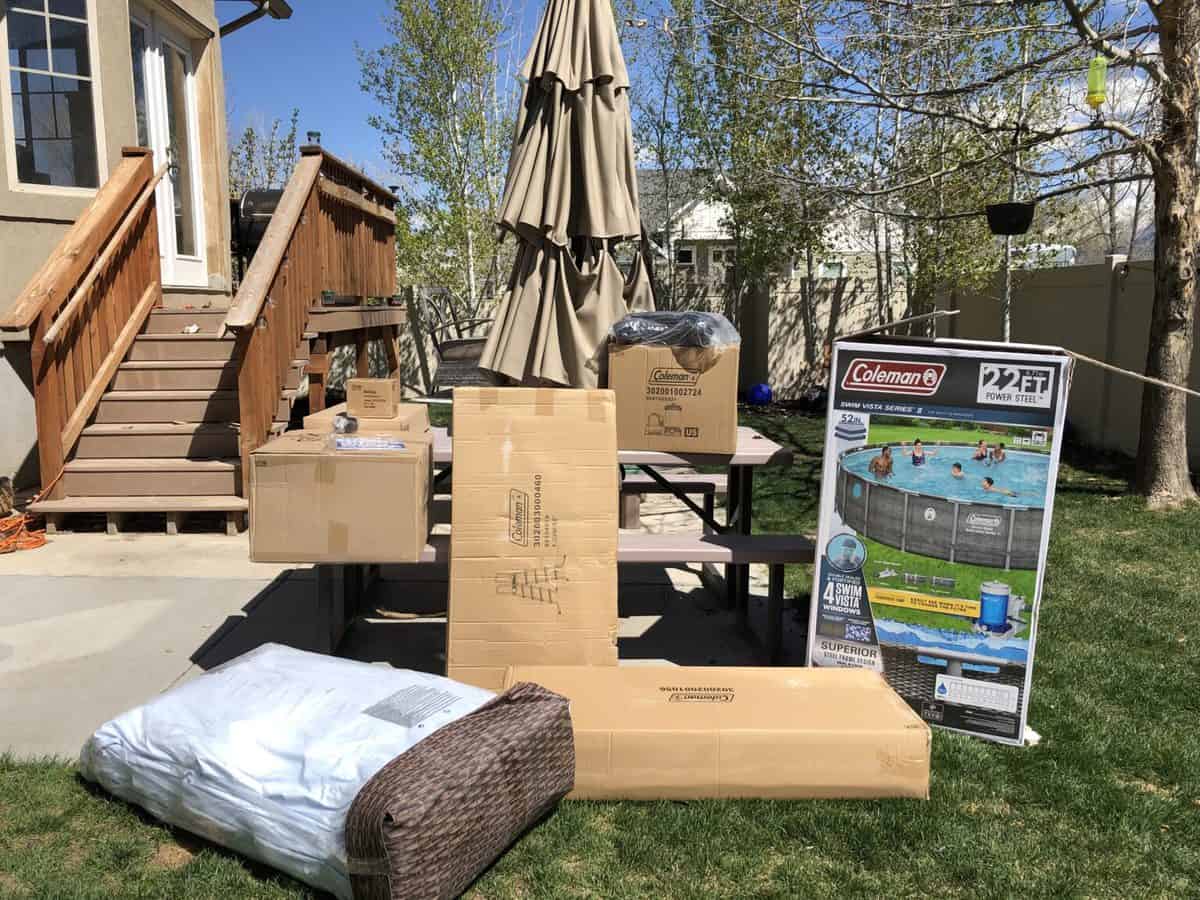 Outdoor patio with new unassembled furniture and a box for a coleman pool.