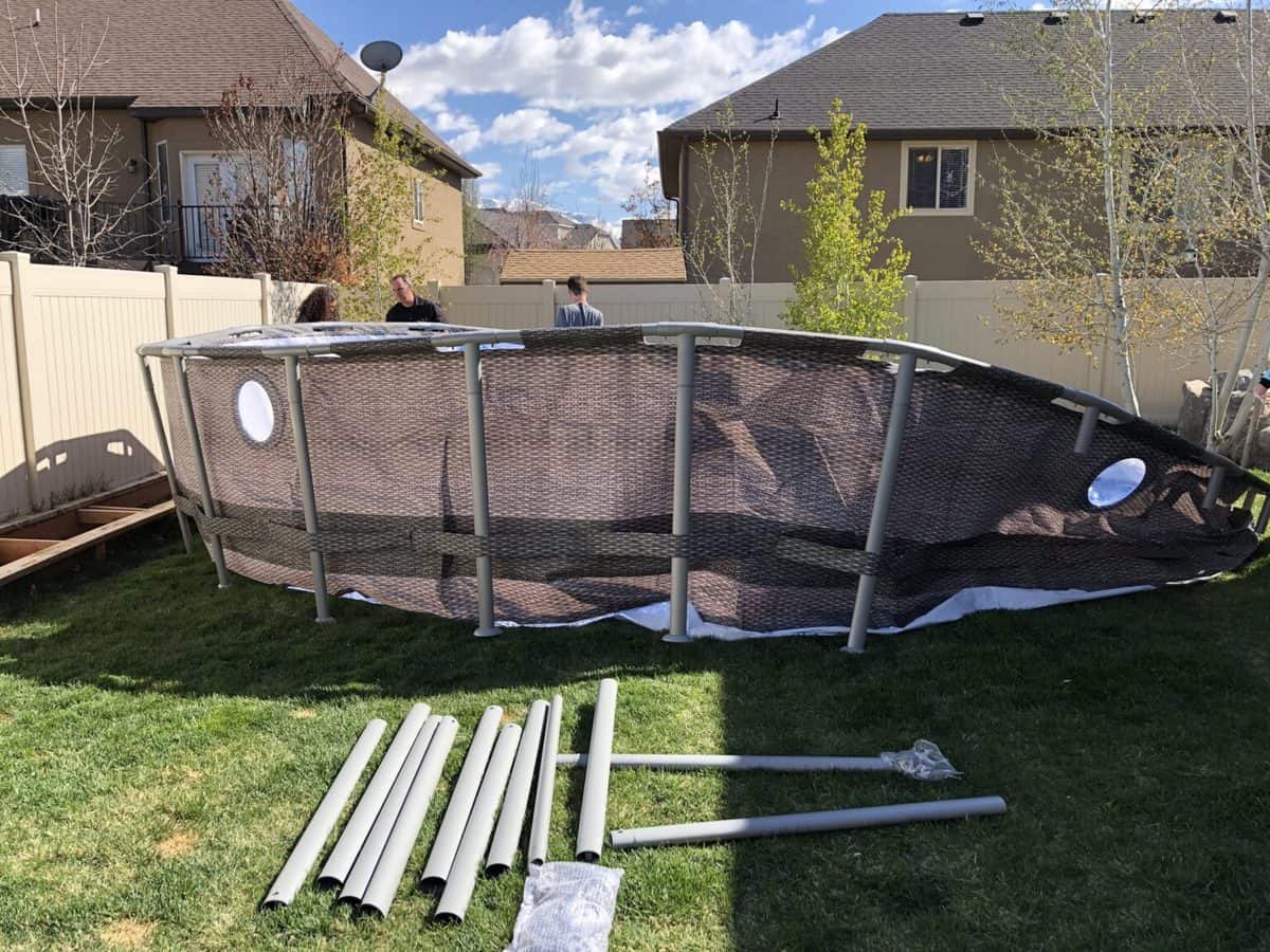 Damaged above-ground pool with disassembled parts on the ground.