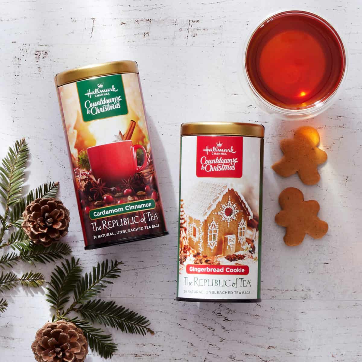Two tins of Hallmark's "Sister Swap: A Hometown Holiday" teas&mdash;cardamom cinnamon and gingerbread cookie flavors&mdash;displayed next to a cup of tea and gingerbread