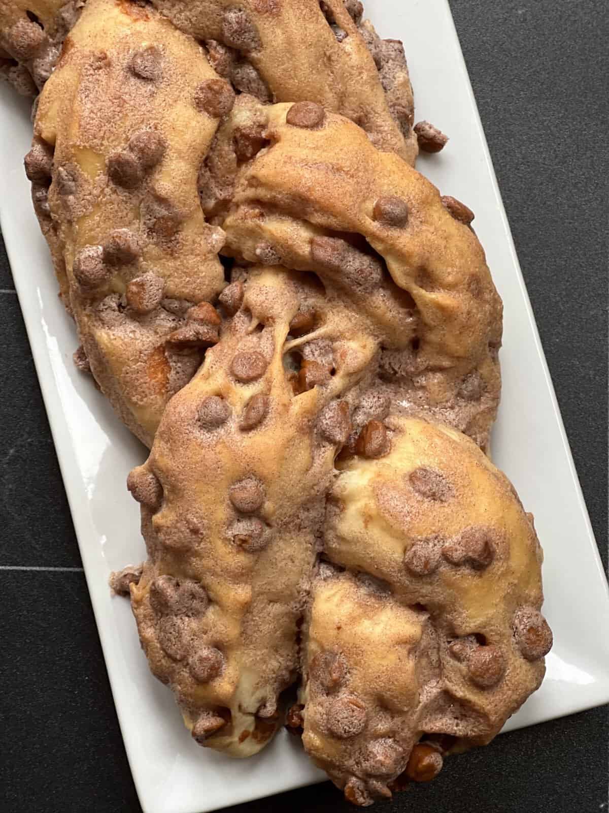 A plate of homemade chocolate chip-studded pastries on a dark surface.