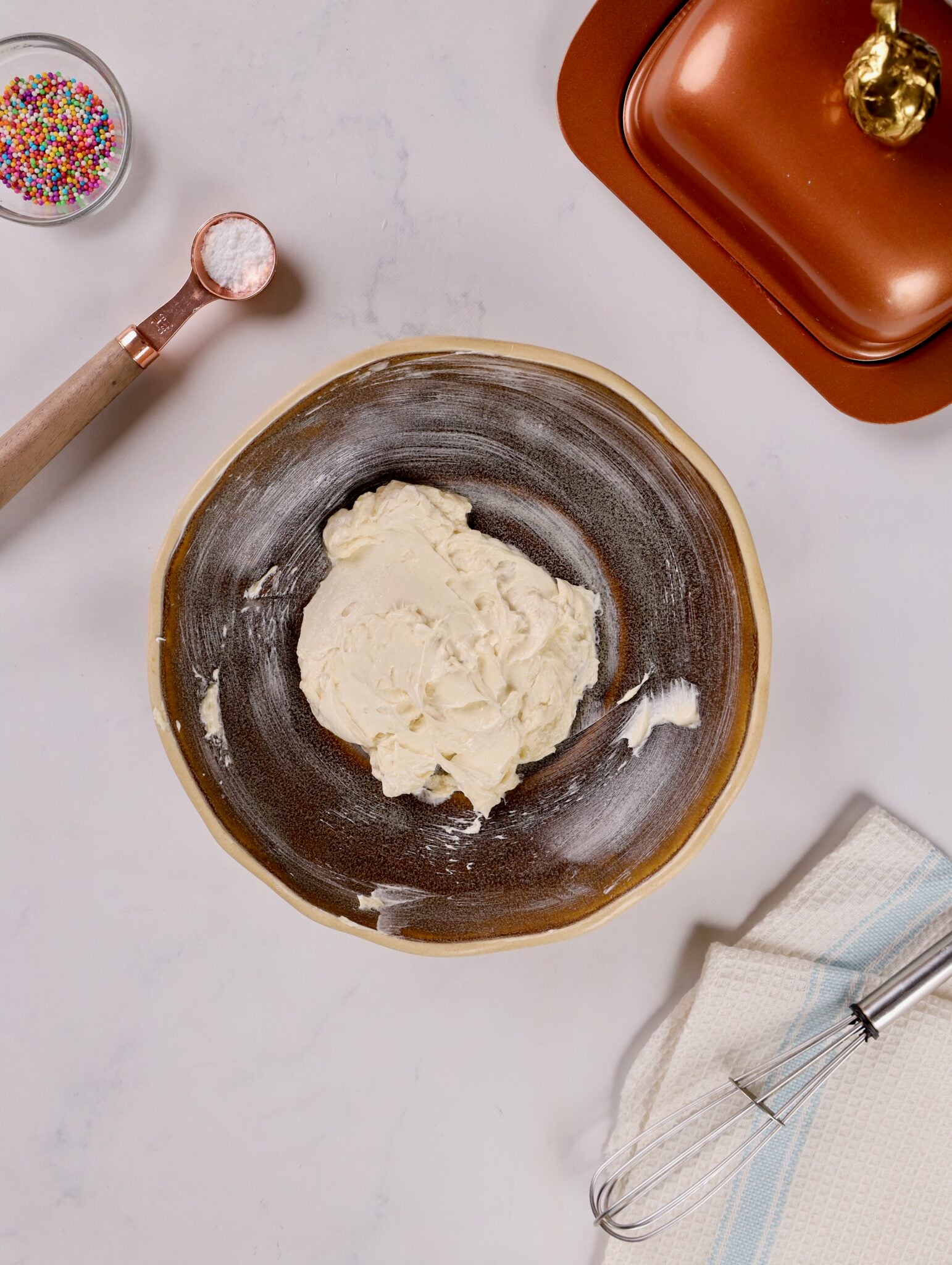 Whisking buttercream ingredients until smooth and creamy in a mixing bowl.