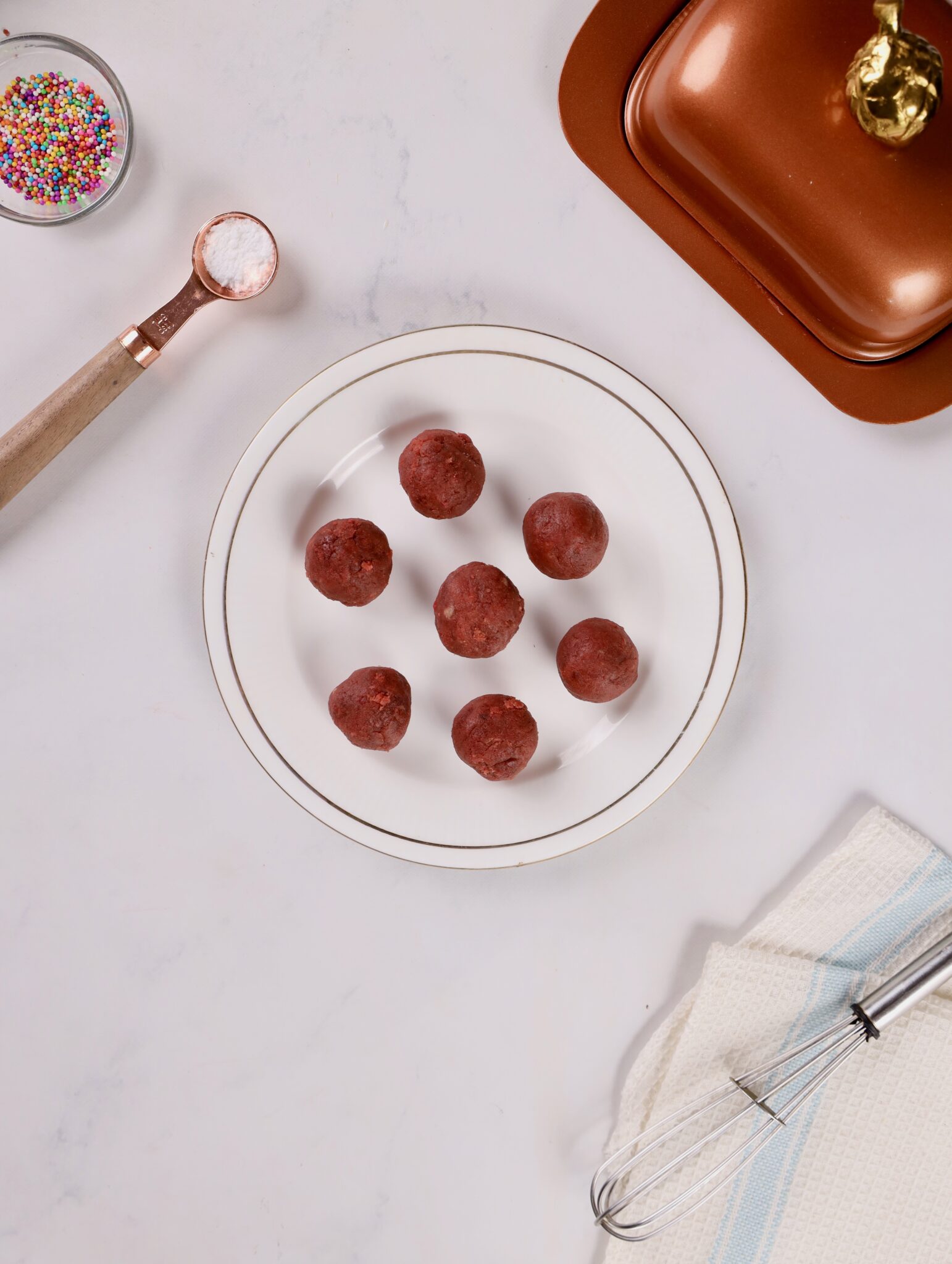 Using an ice cream scoop to form uniform red velvet cake balls.