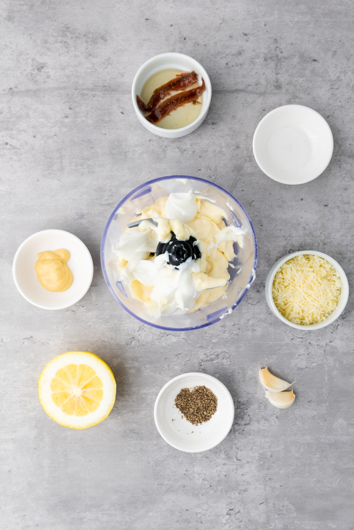 Pouring in a quarter cup of thick Greek yogurt, juxtaposed against the already added mayonnaise.