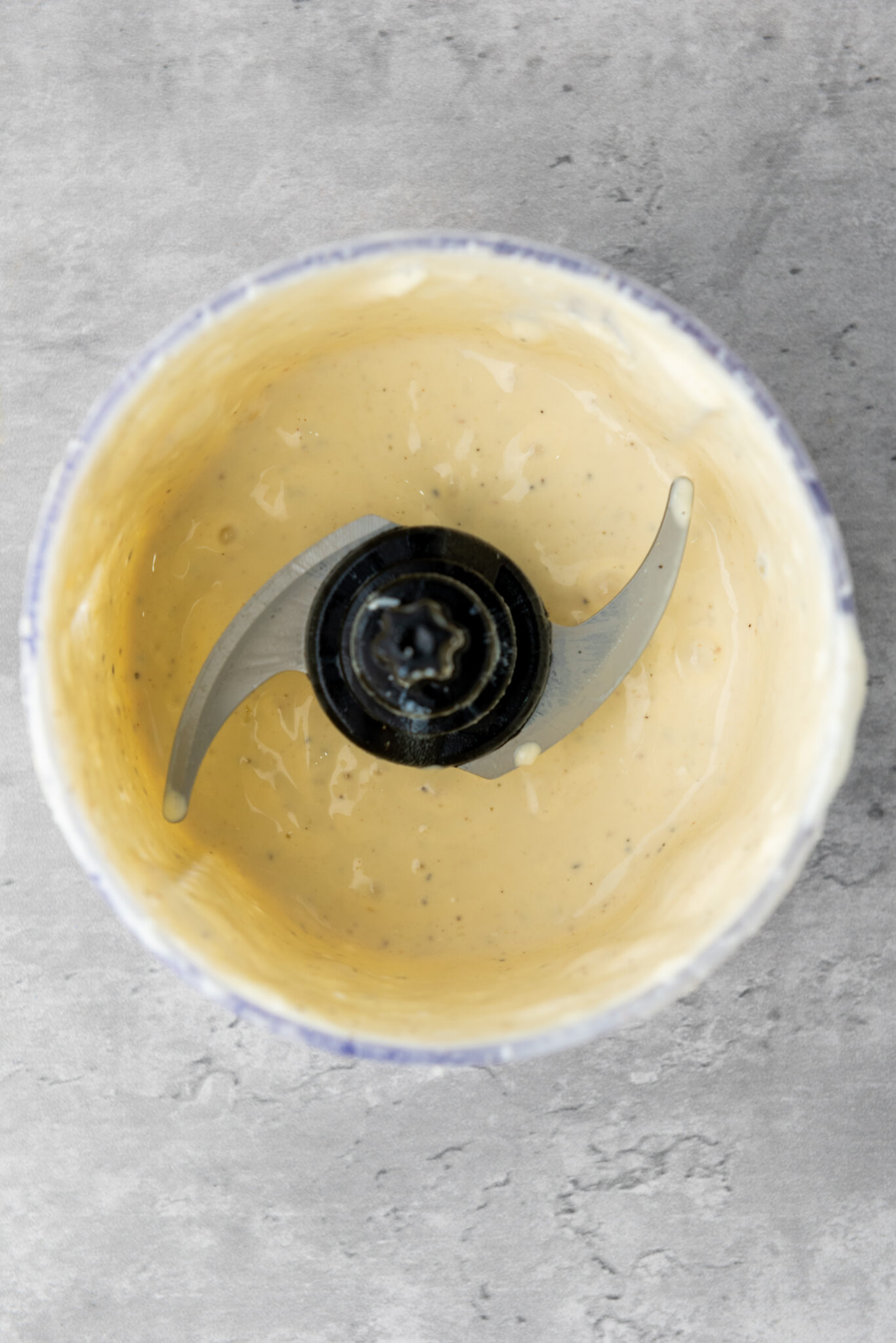 he processor, after blending the ingredients into a smooth, creamy Caesar dressing, with a whirl of textures visible.