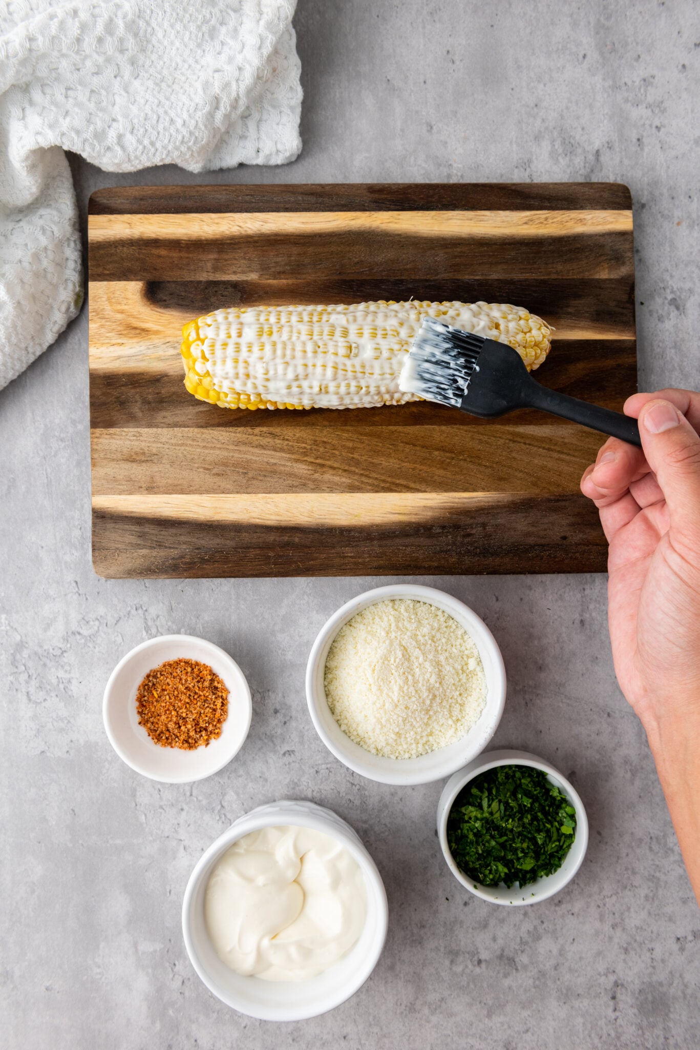Applying the creamy sauce onto the cooked corn using a pastry brush