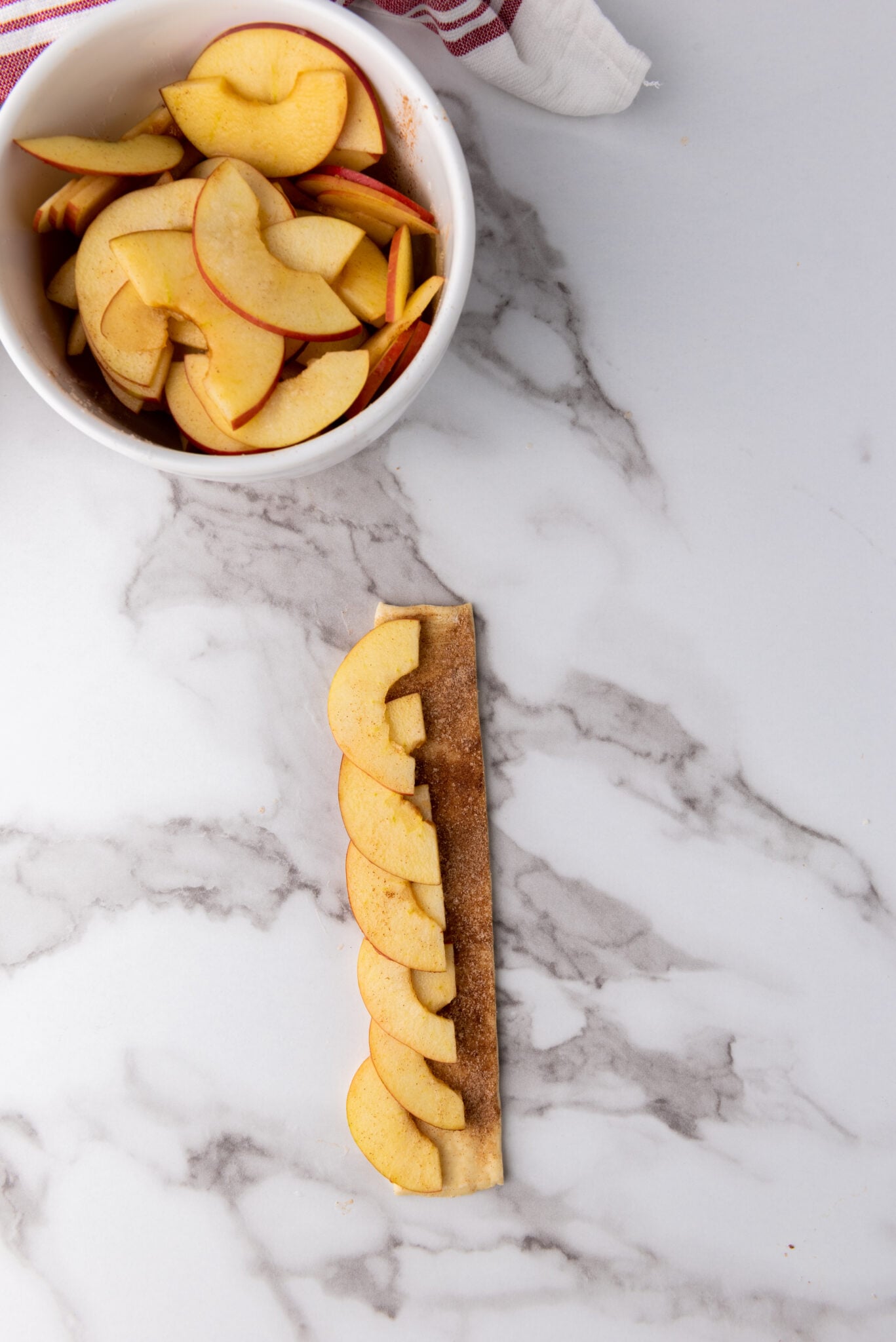 apples lined up on pastry dough
