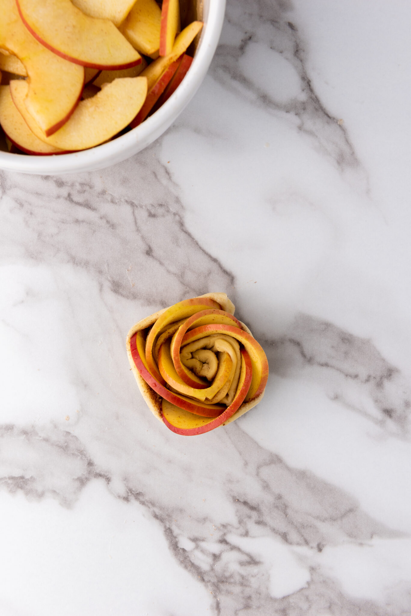 delicately rolling the apple-filled pastry into a rose shape
