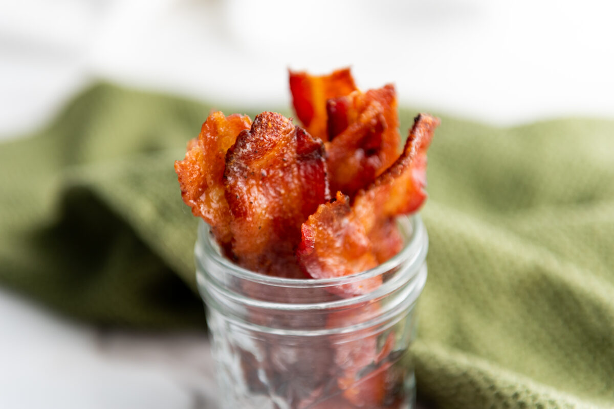 Several strips of maple-candied bacon artistically layered, showcasing the glistening candied texture.