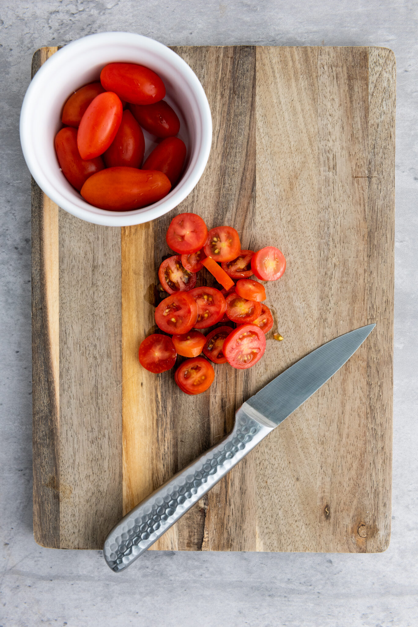 Slicing cherry tomatoes on a chopping board.