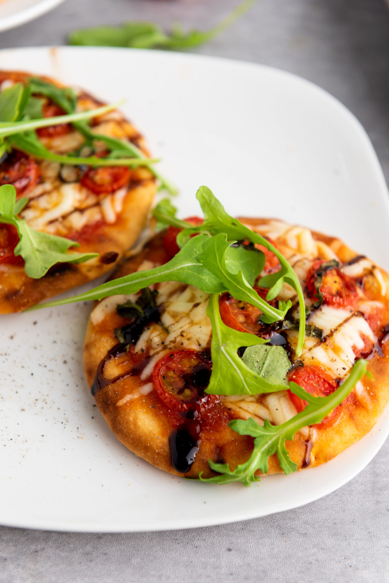Overhead shot of Caprese pizzas garnished with arugula, ready to be served.