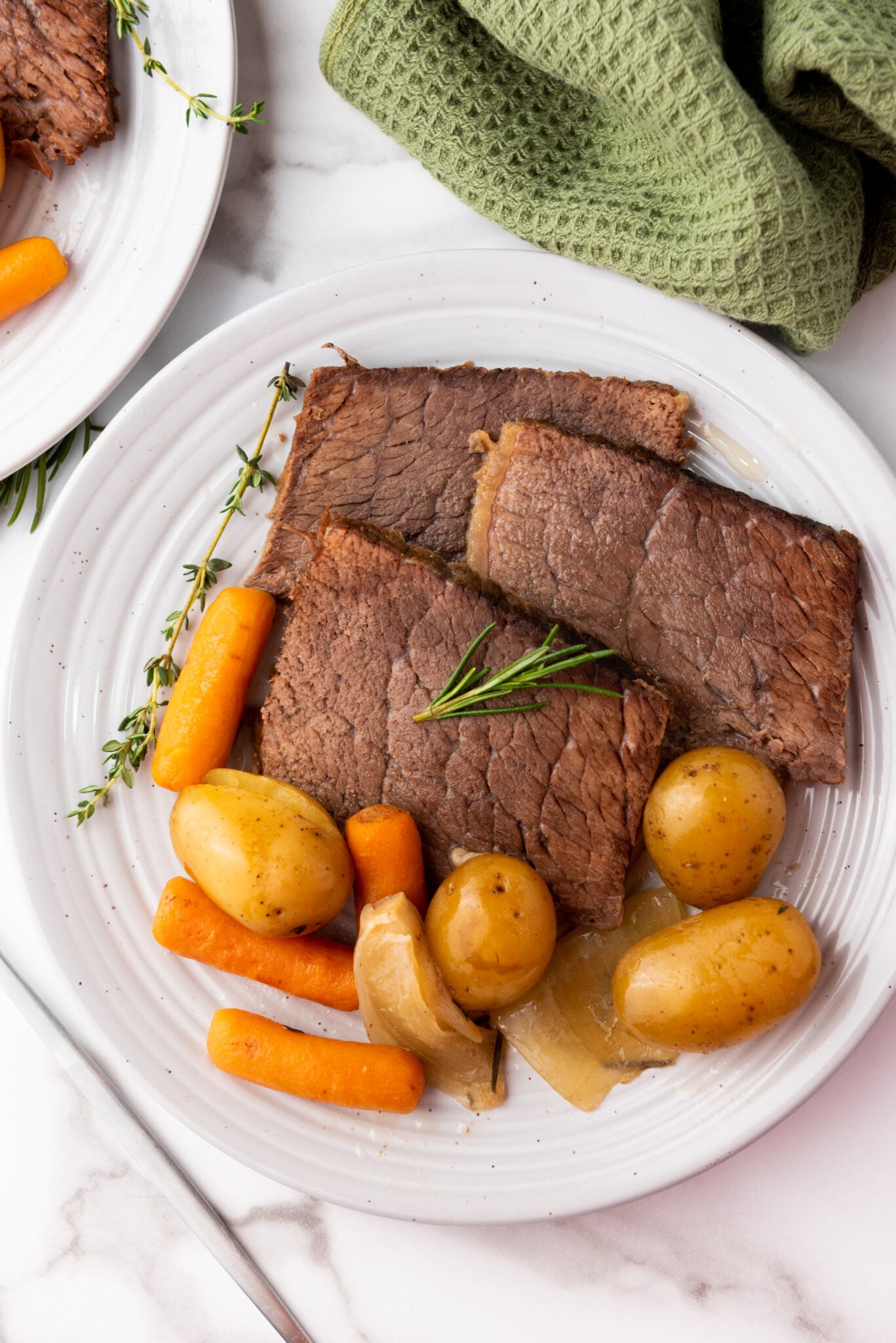 Sliced meat revealing its tender and juicy inside, with a serving of baby potatoes and carrots on a plate.