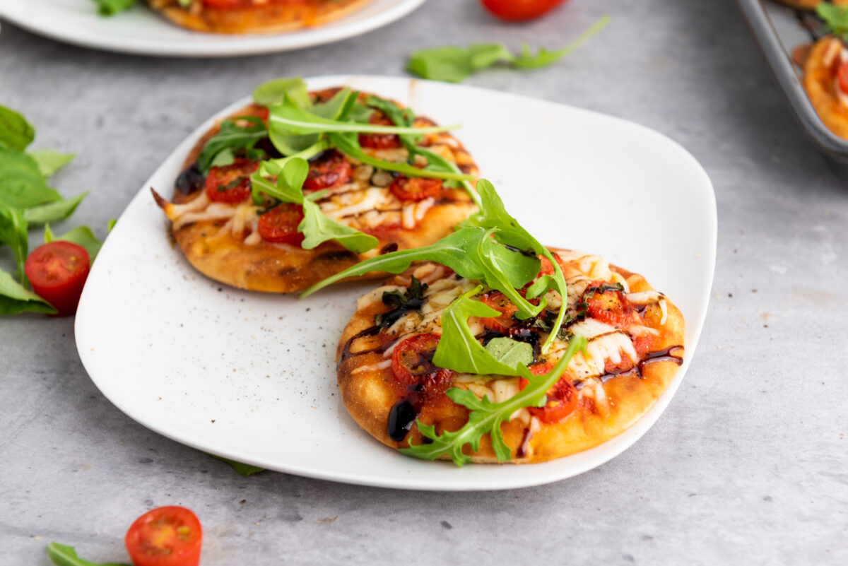 Caprese pizza showcasing melted mozzarella, tomatoes, and a drizzle of balsamic glaze.