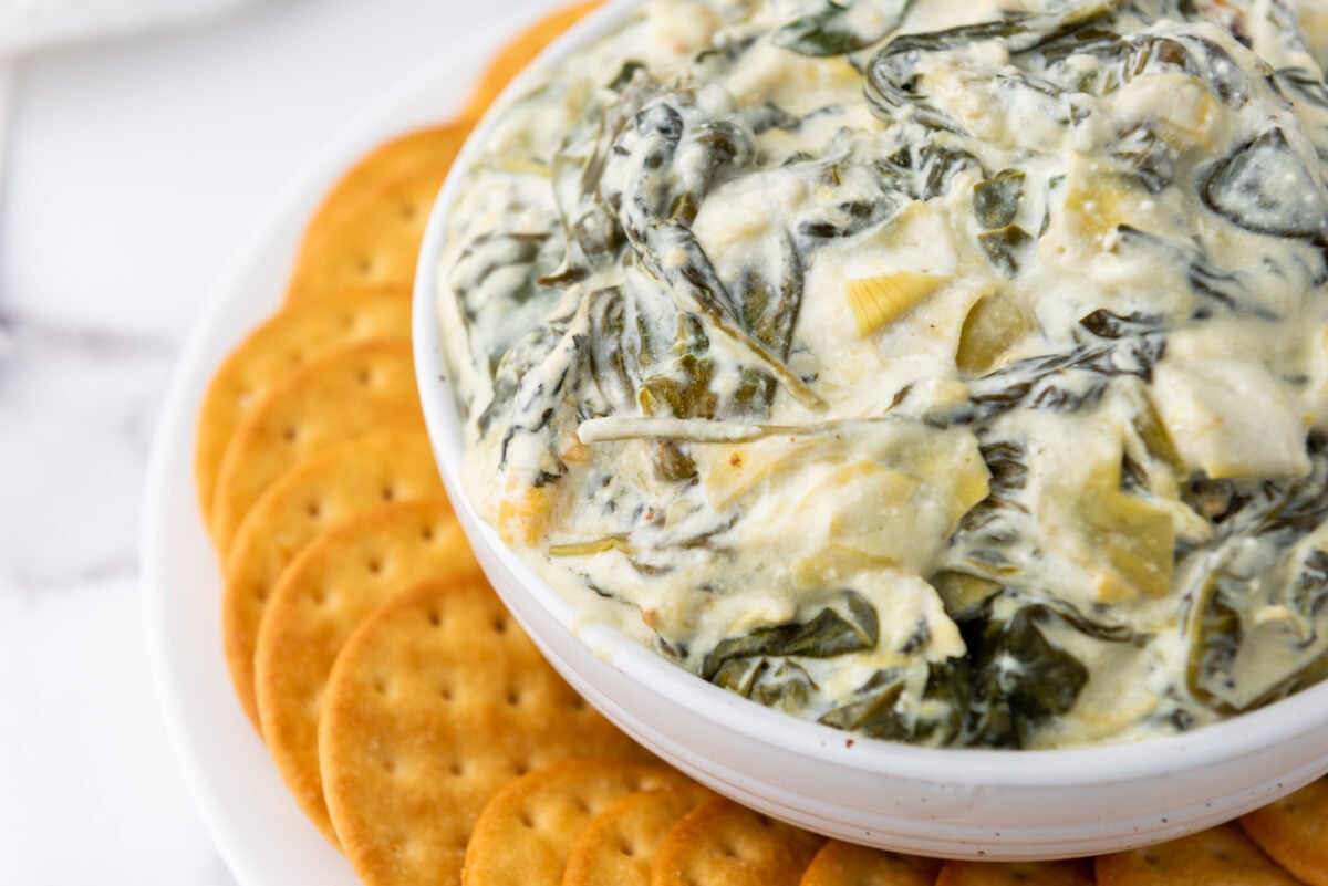 A beautifully presented bowl of creamy spinach artichoke dip, its golden-brown surface indicating a perfect cook.