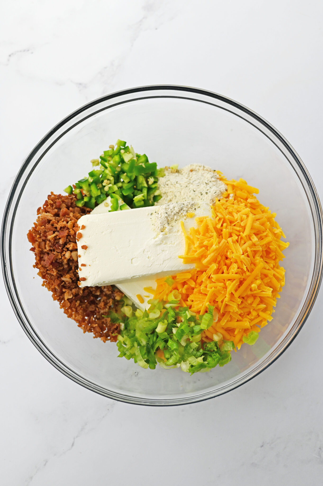 adding Ingredients: Ingredients like cream cheese, cheddar, and spices being thoroughly mixed in a bowl.