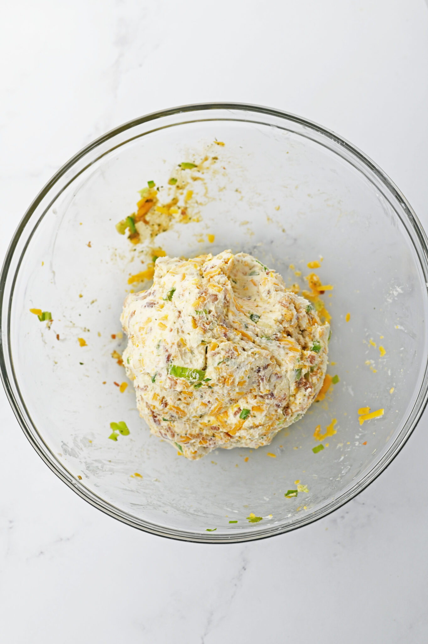 mixing Ingredients: Ingredients like cream cheese, cheddar, and spices being thoroughly mixed in a bowl.
