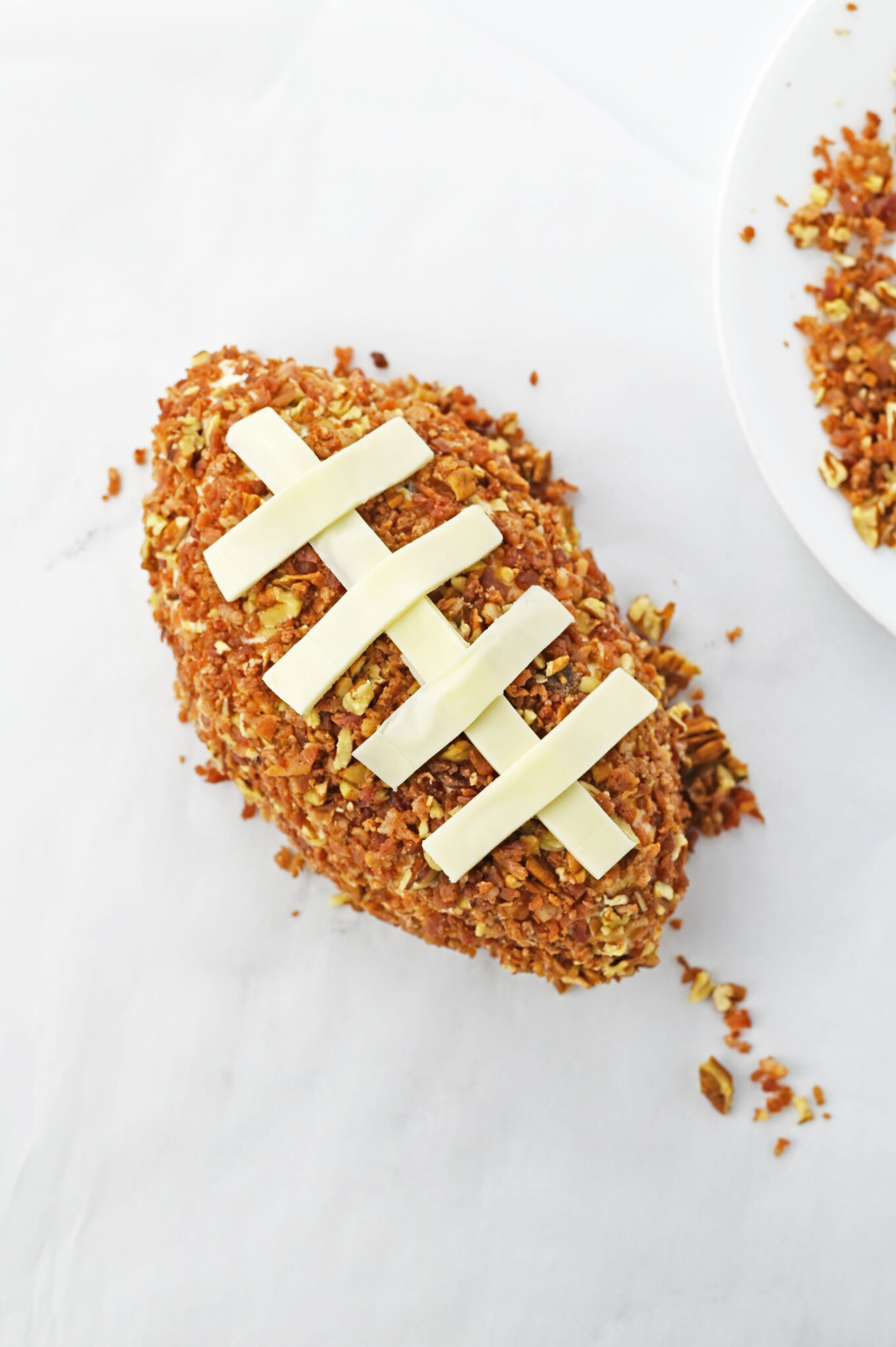 Decorating the Football: Adding thin slices of cheddar on top to resemble the football's stitching.