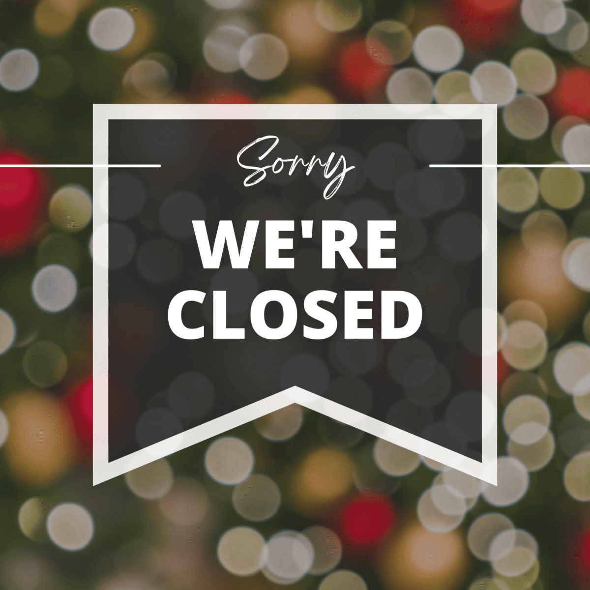 Sign reading 'sorry we're closed for Christmas' with blurred festive lights in the background.