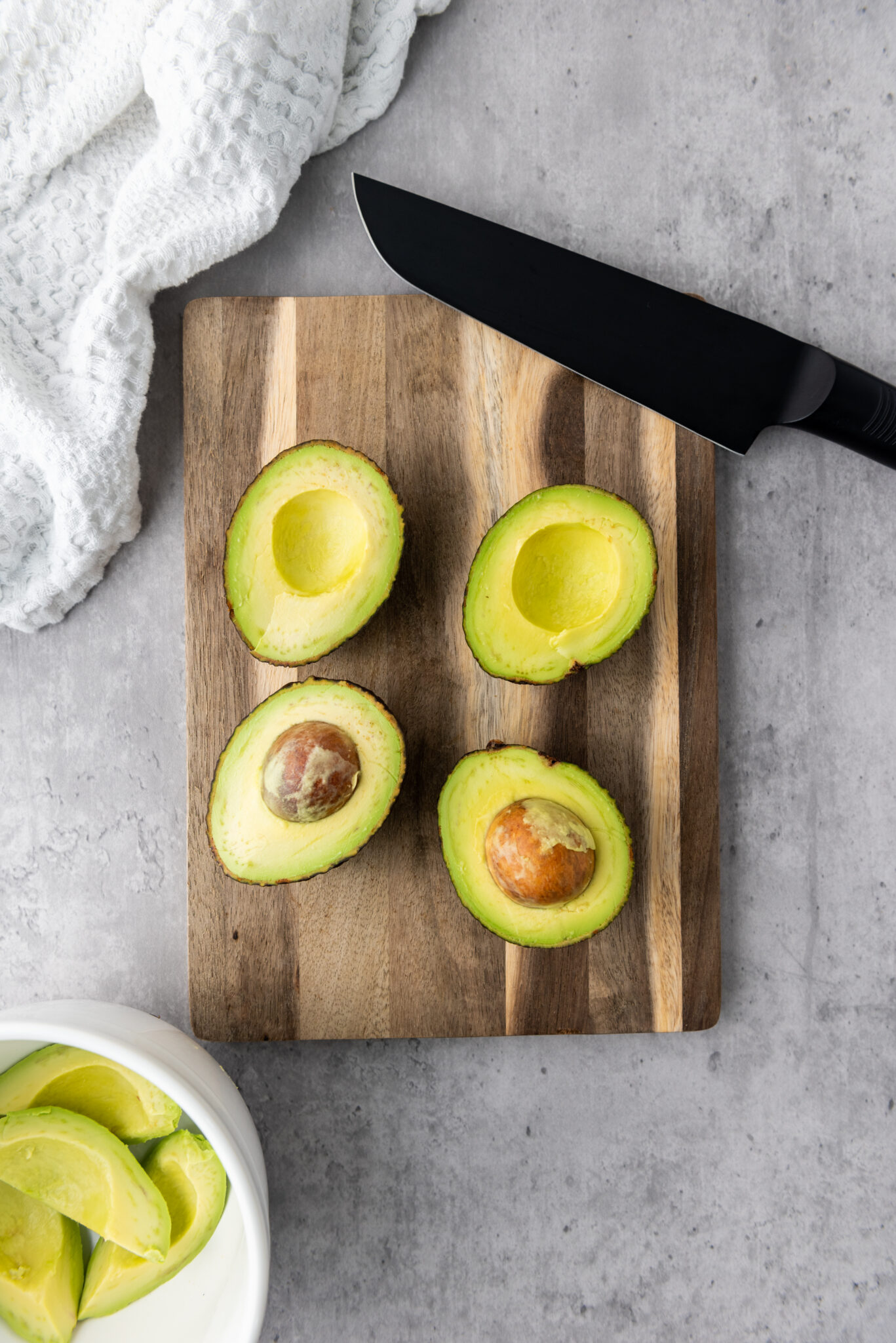 Halved avocados with removed pits placed in a bowl.