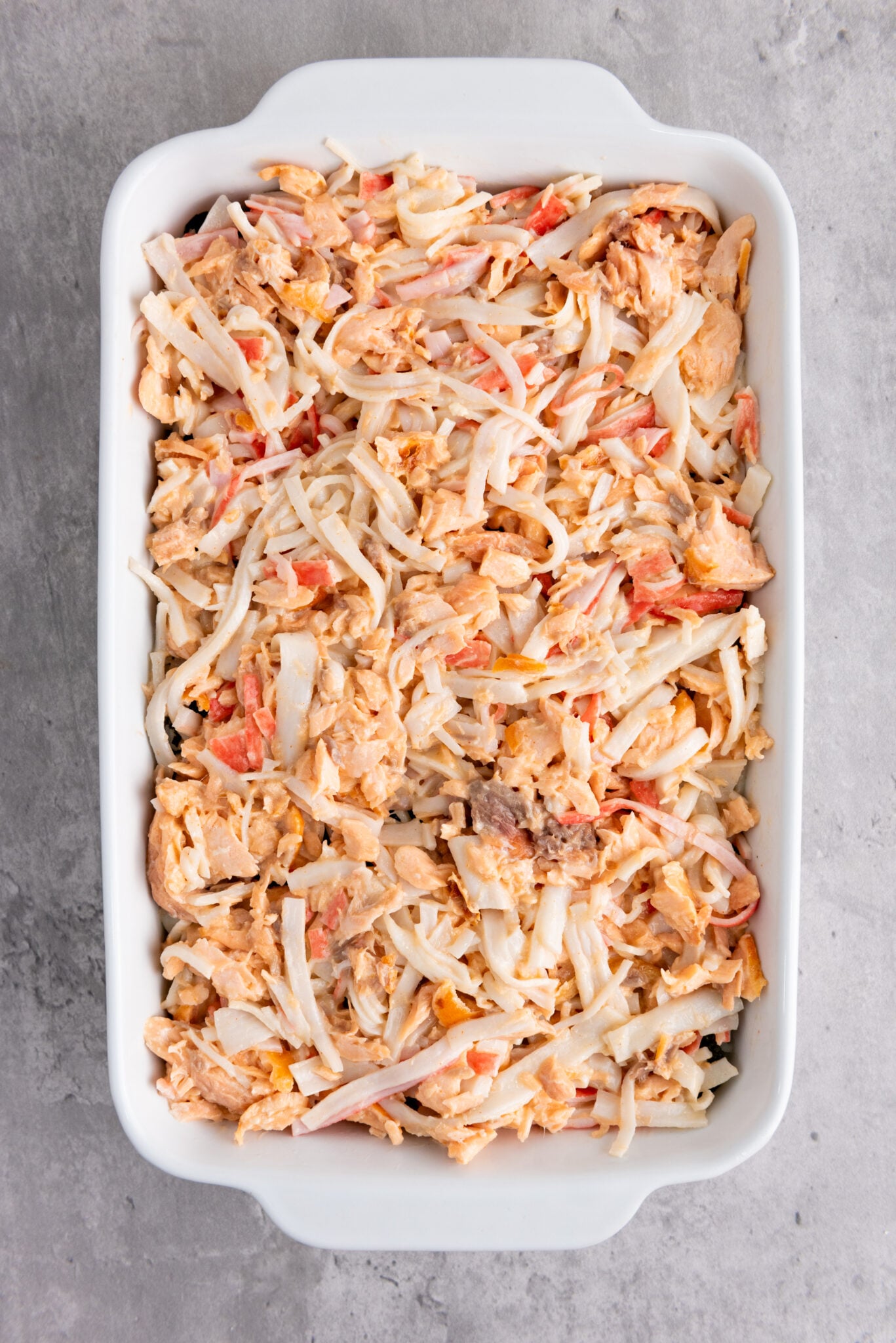 Salmon and crab mix spread over nori sheets in a casserole dish.