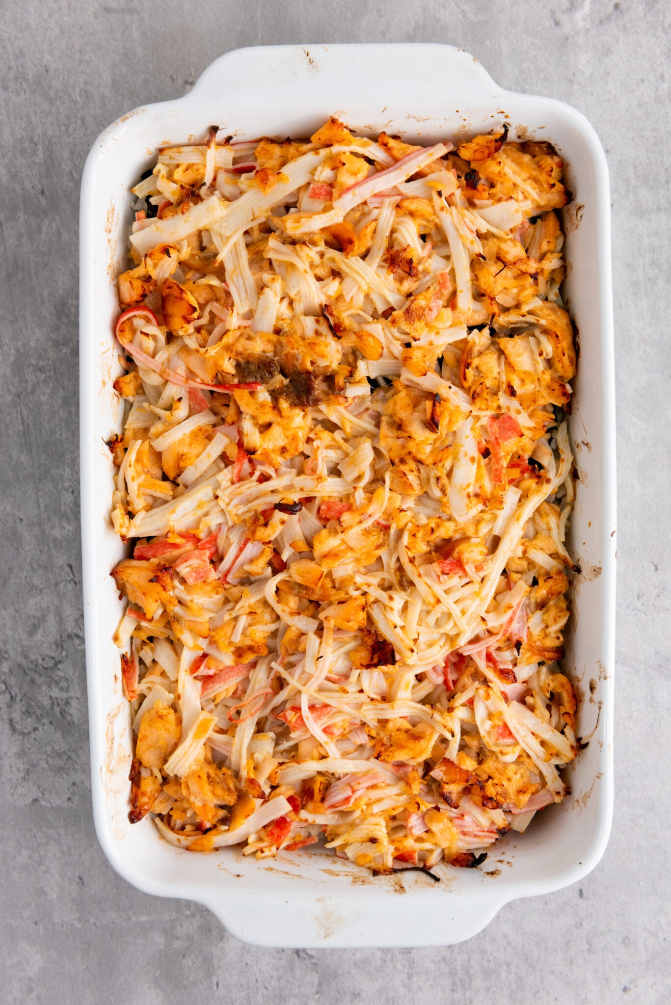 Casserole dish with sushi bake taken out of the oven, golden on top.