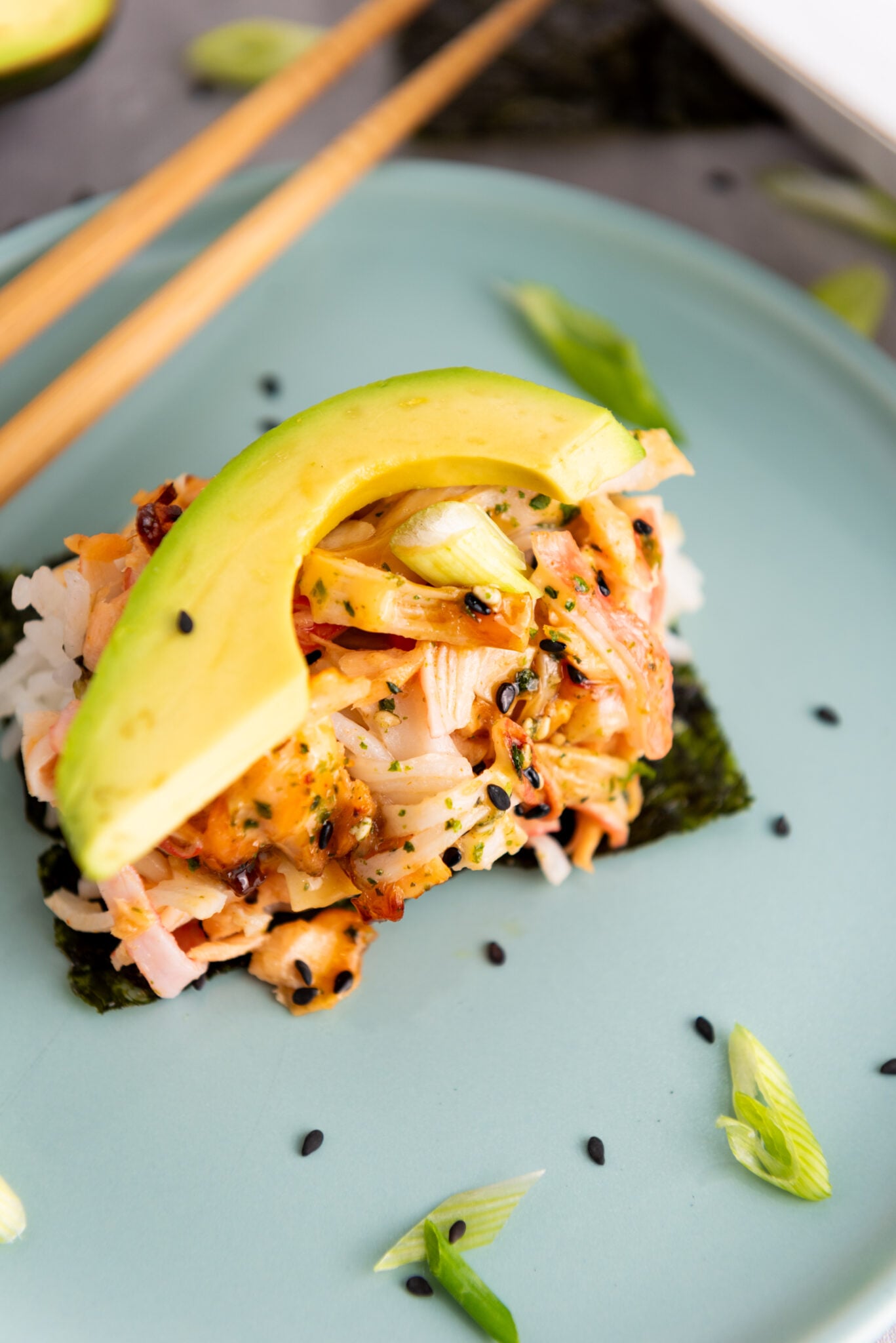 Side view of sushi bake piece on a plate with chopsticks, ready to be enjoyed.