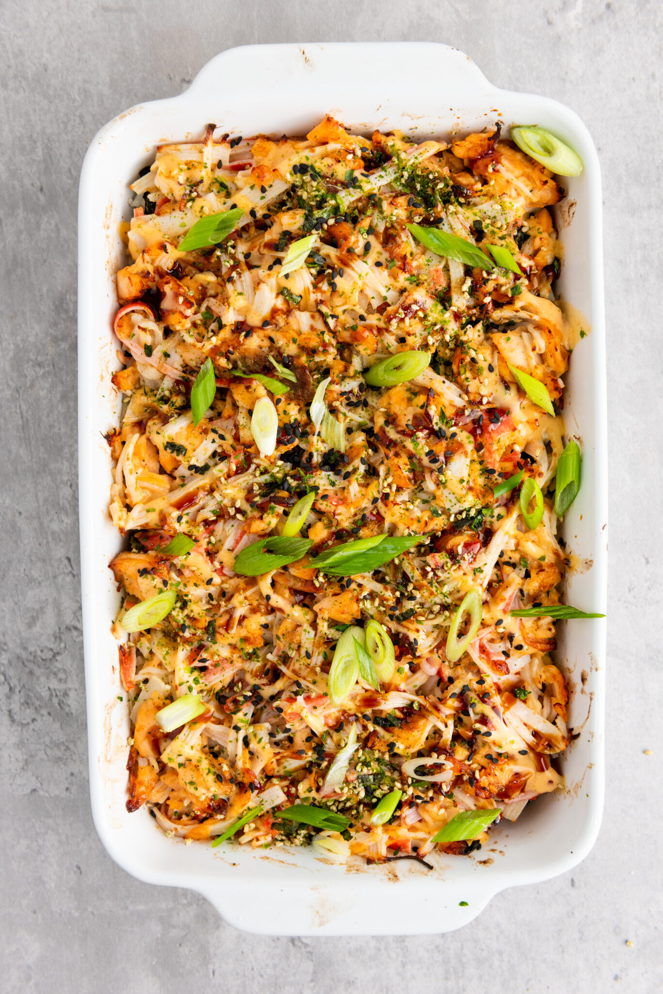 Close-up of sushi bake topped with sauces, seasonings and scallions