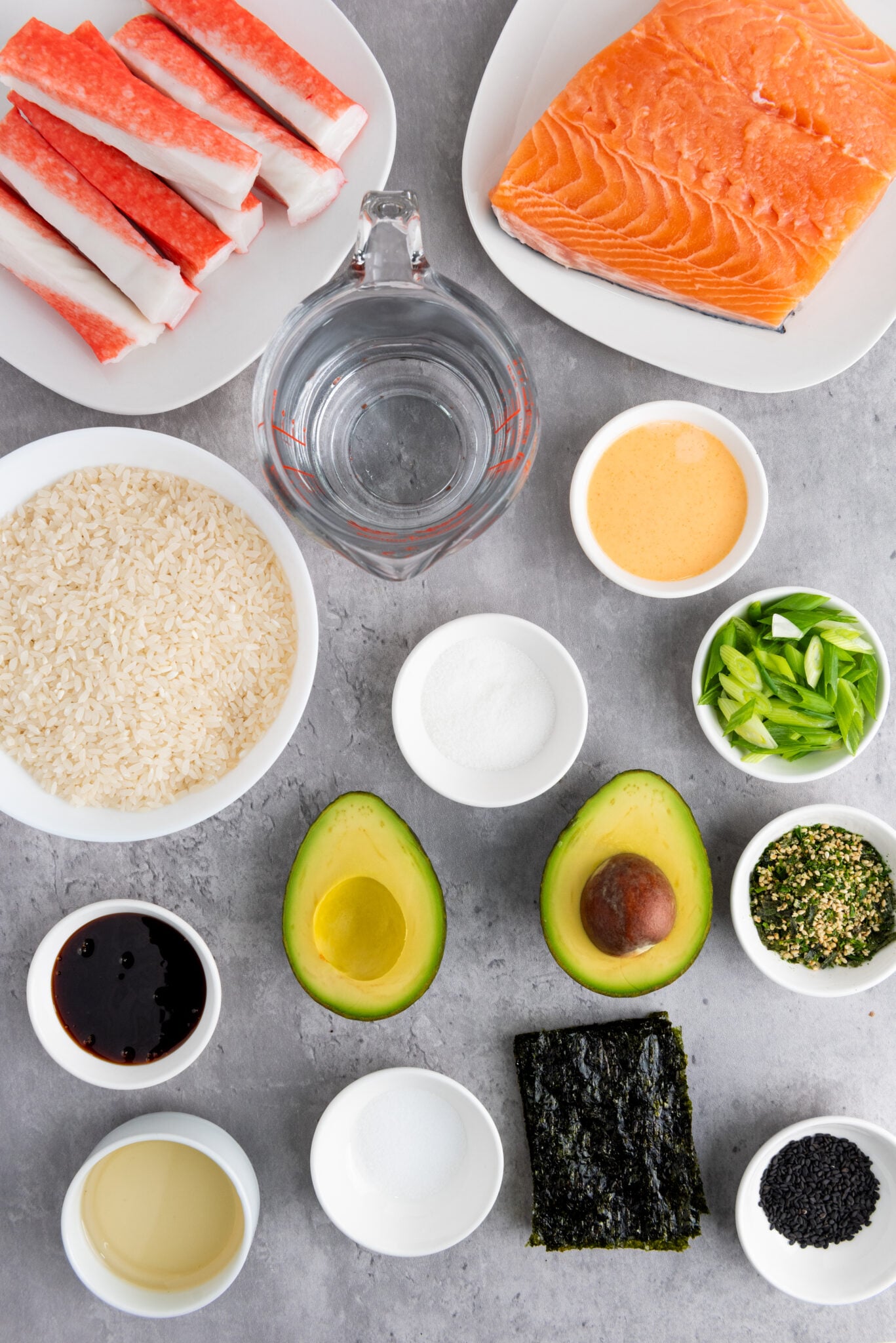 Flat lay of all sushi bake ingredients, neatly arranged on a marble countertop.
