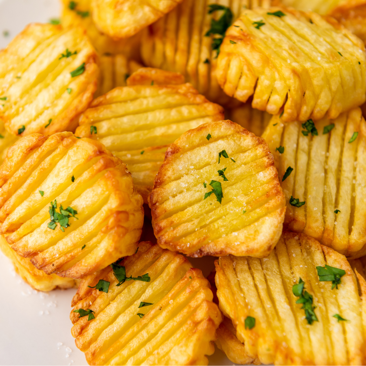 Close-up of golden-brown accordion potatoes garnished with herbs.