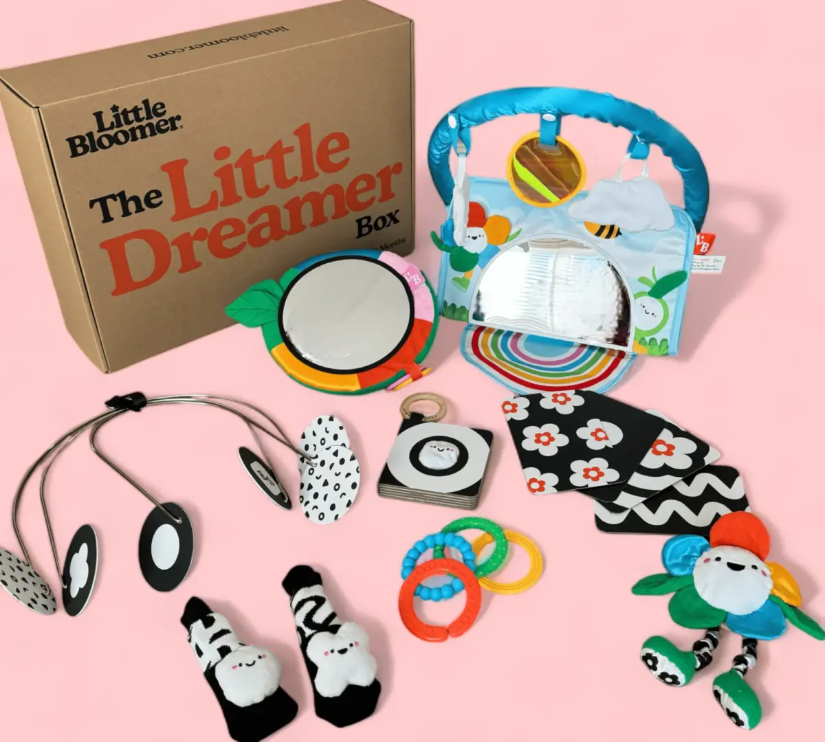 A collection of baby items, including toys, socks, and a play mat, displayed alongside "the little dreamer box" packaging.