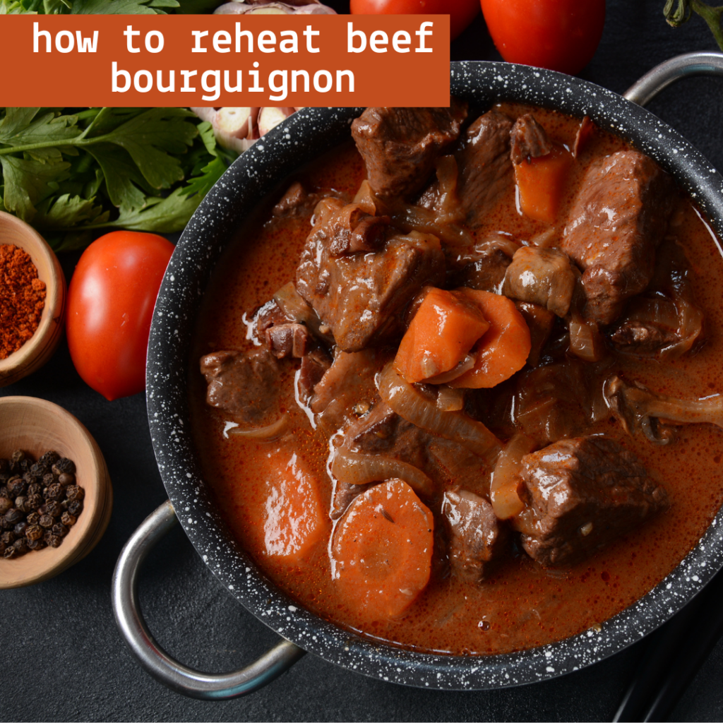 A pot of beef bourguignon with chunks of beef, carrots, and a rich sauce, accompanied by garlic, tomatoes, pepper, and spices. text overlay: "how to reheat beef bourguignon.