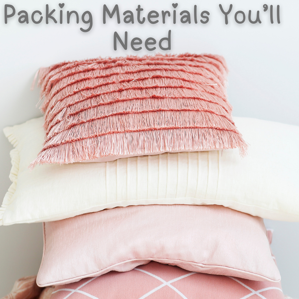 Three decorative pillows stacked under the text "Packing Materials You'll Need" offer a glimpse into moving tips. Discover the best way to pack pillows seamlessly for your move.