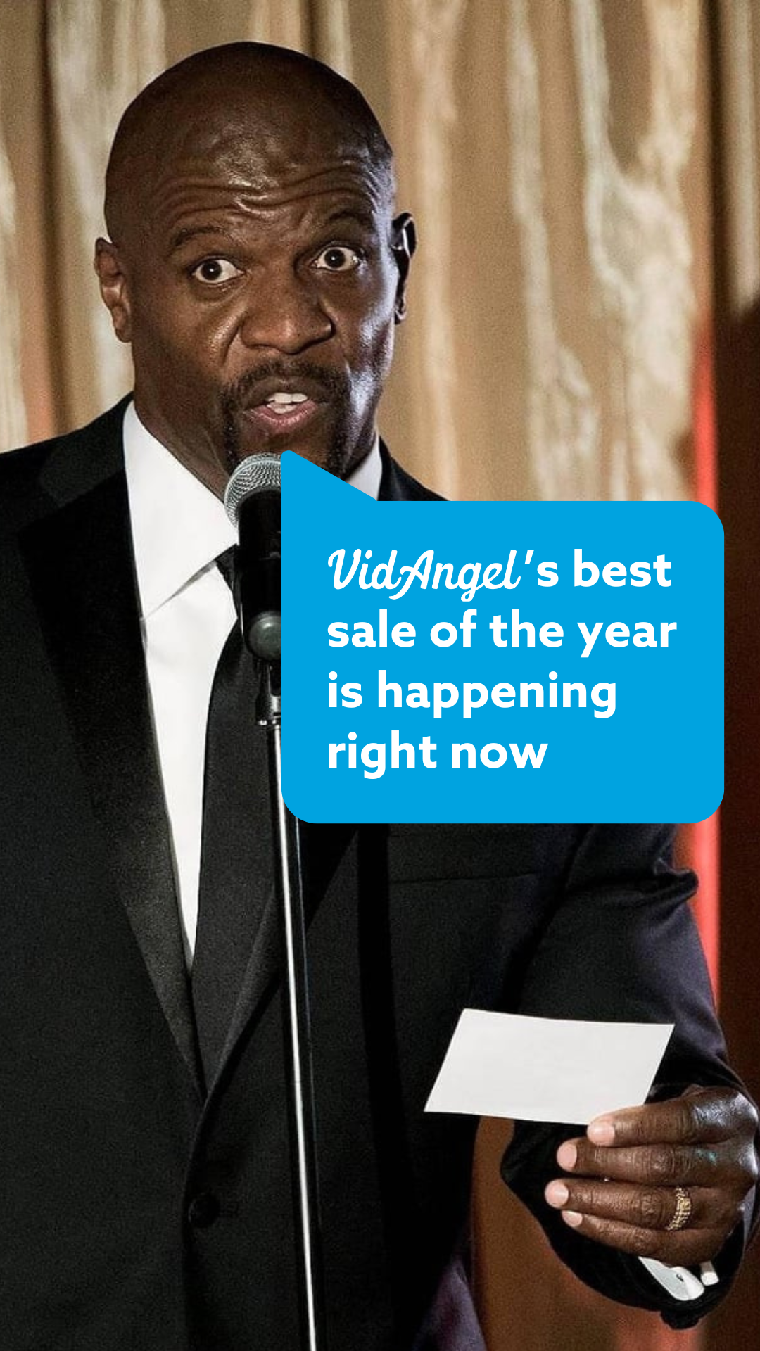 A man in a suit speaks into a microphone, holding a piece of paper. Nearby, a blue speech bubble announces, "VidAngel's best Black Friday sale is happening right now. Use your coupon code today!