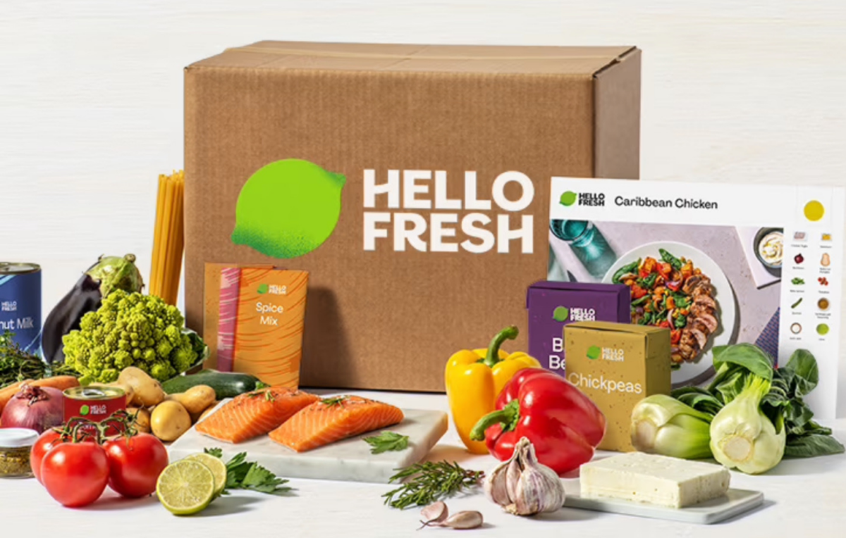 The HelloFresh Box arrives packed with fresh ingredients like salmon, peppers, tomatoes, broccoli, chickpeas, and a spice mix. Unbox your culinary adventure featuring a recipe card for Caribbean Chicken and enjoy the first taste with your free box offer!.