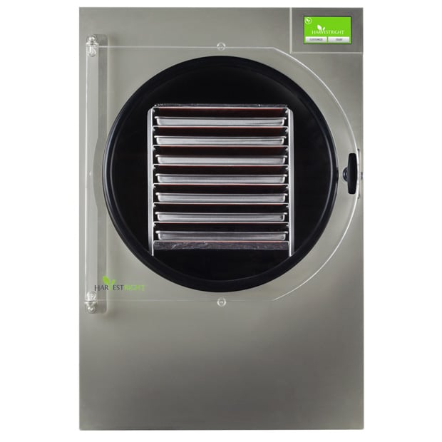 A front view of a Harvest Right stainless steel freeze dryer with a transparent door and several metal trays inside—unlock savings with a Coupon Code.